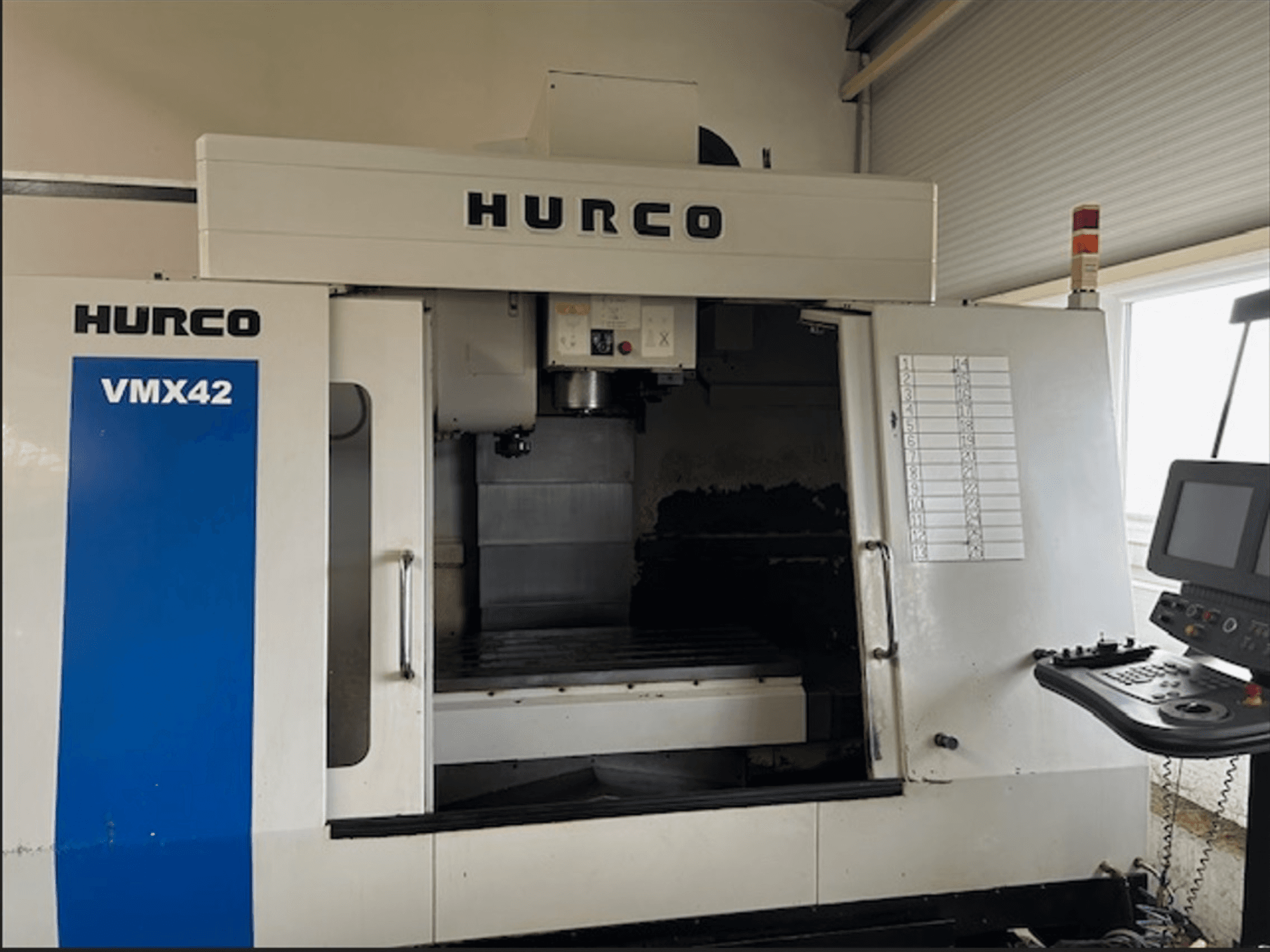 Hurco VMX42 CNC marógép, előlnézet, vezérlőpanel és nyitott munkaterület a megmunkálási műveletekhez.