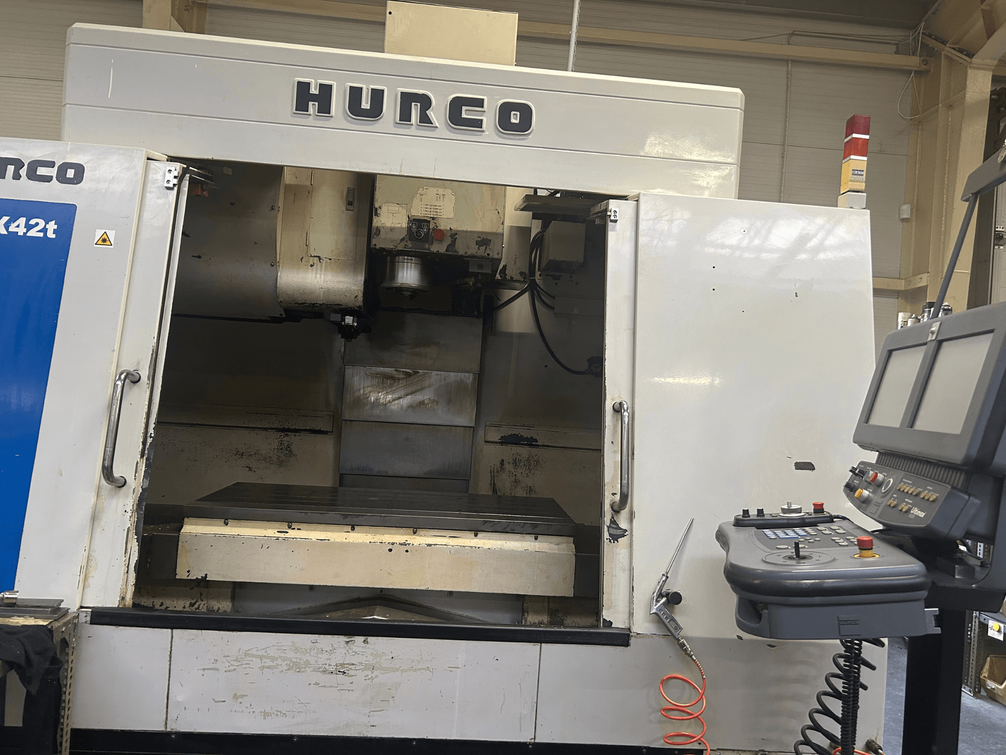 Hurco VMX42T CNC marógép elölnézetben, nyitott munkaterülettel, valamint gombokkal és kijelzővel ellátott vezérlőpanellel.