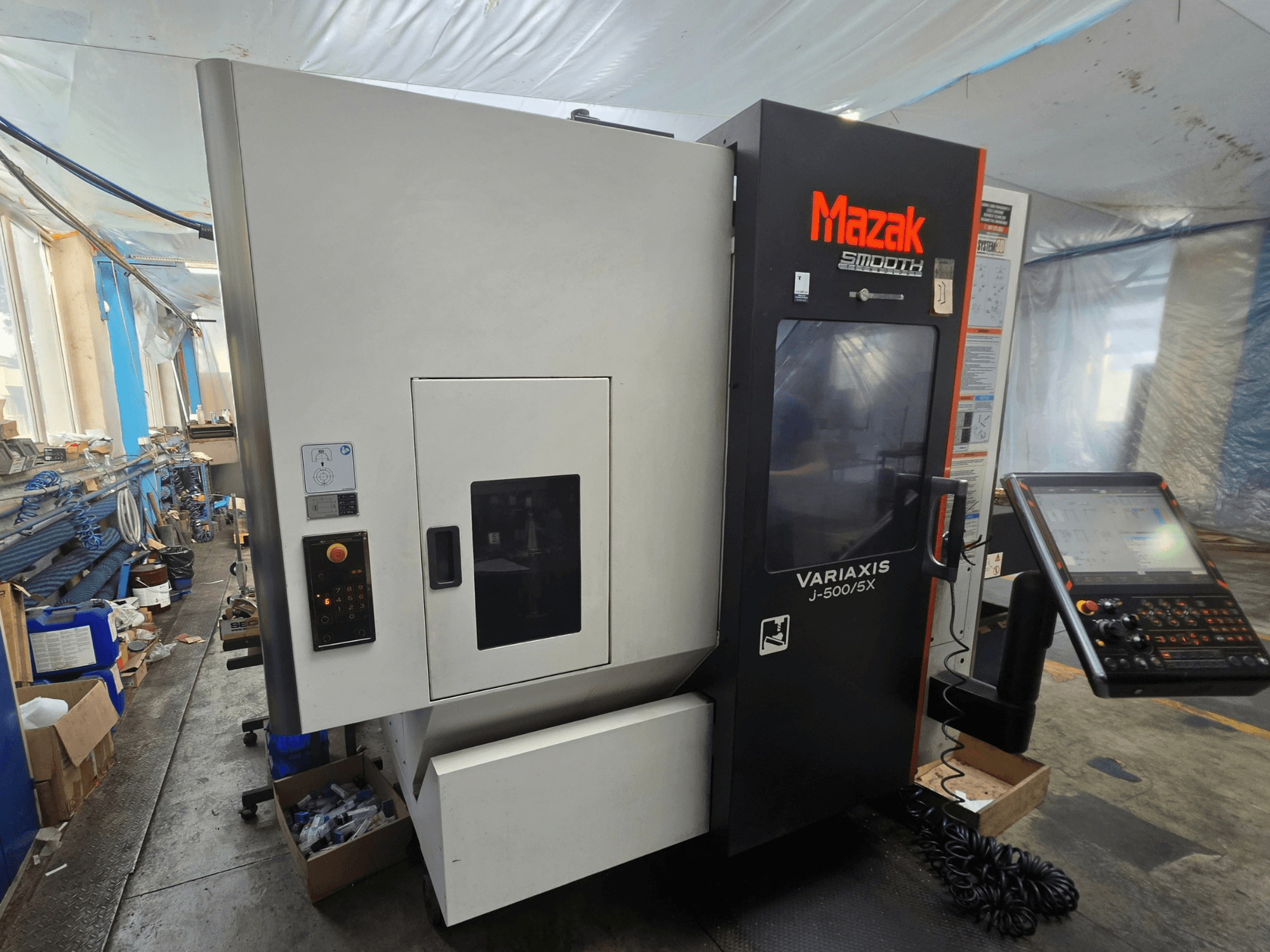 Mazak VARIAXIS J-500/5X függőleges megmunkáló központ, oldalnézet a kezelőszervekkel és a kijelzővel, műhelyi környezetben.