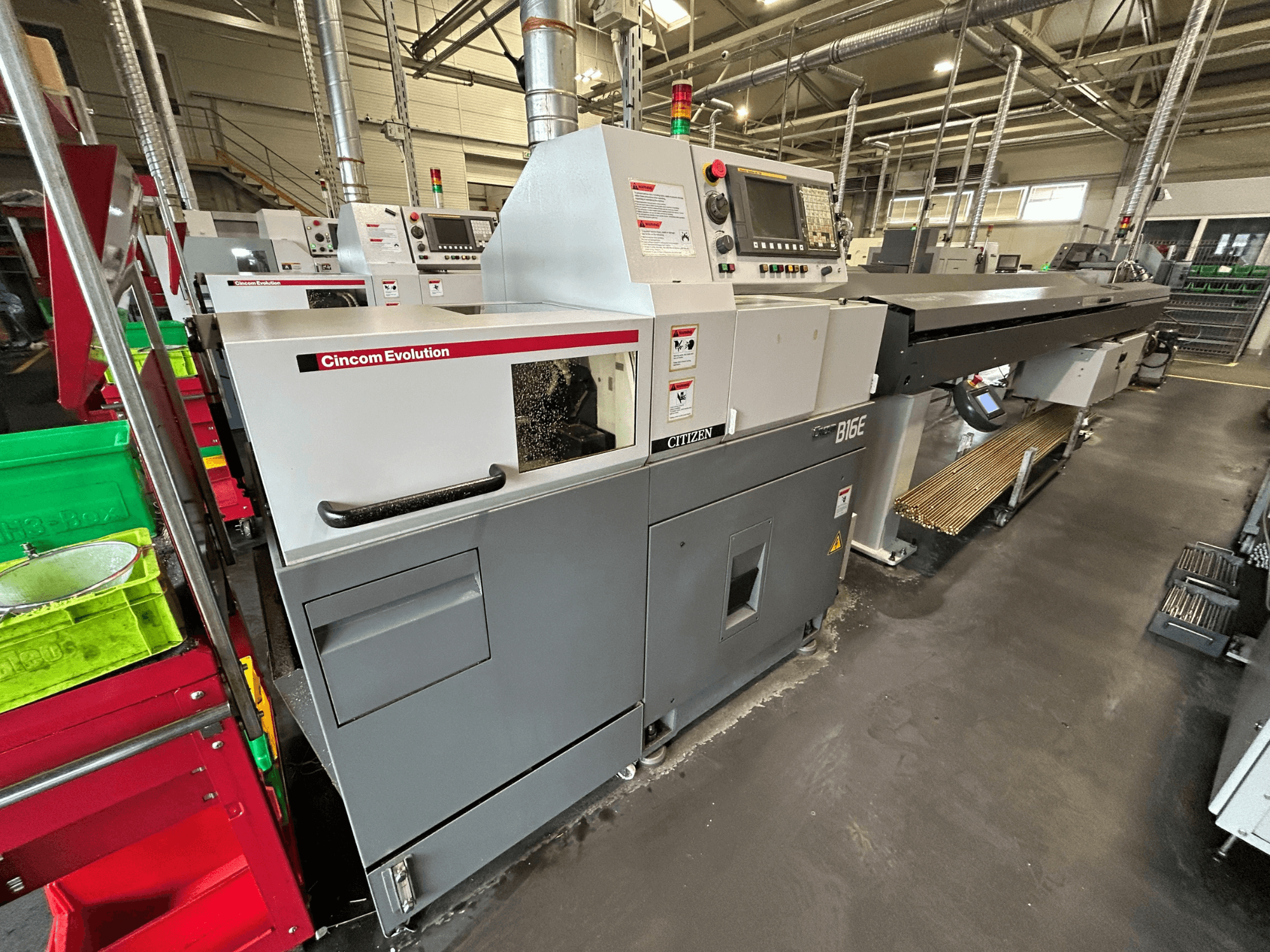 A Citizen B16 vízszintes eszterga oldalnézetben, a vezérlőpanellel, a munkaterülettel és a közelben elhelyezett anyagtartályokkal.