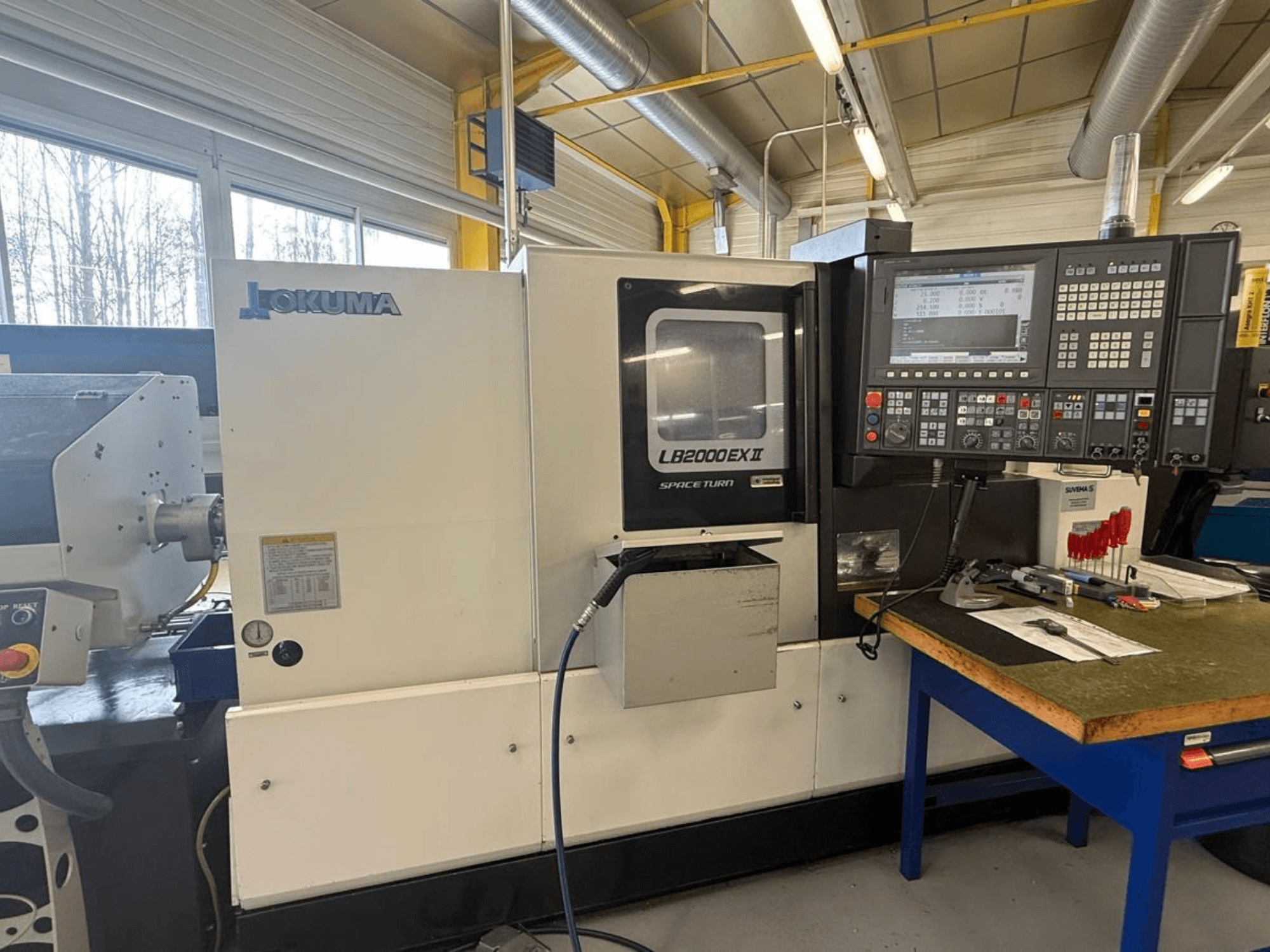Okuma LB2000EX II vízszintes esztergagép, elölnézet; vezérlőpanel, orsóterület és a környező munkaterület.