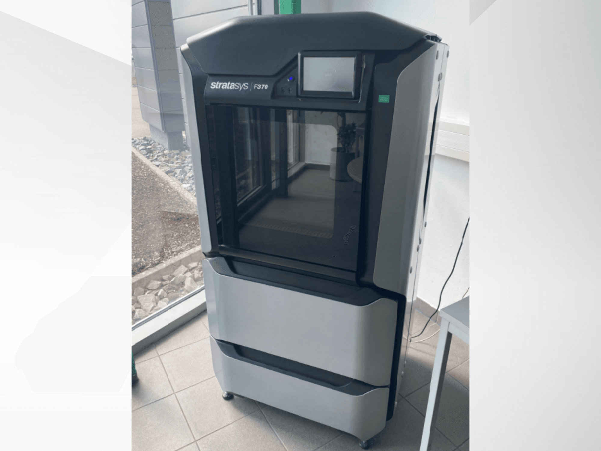 Stratasys F370 műanyag 3D nyomtató, előlnézet, elegáns fekete-szürke dizájn, érintőképernyős kijelzővel.