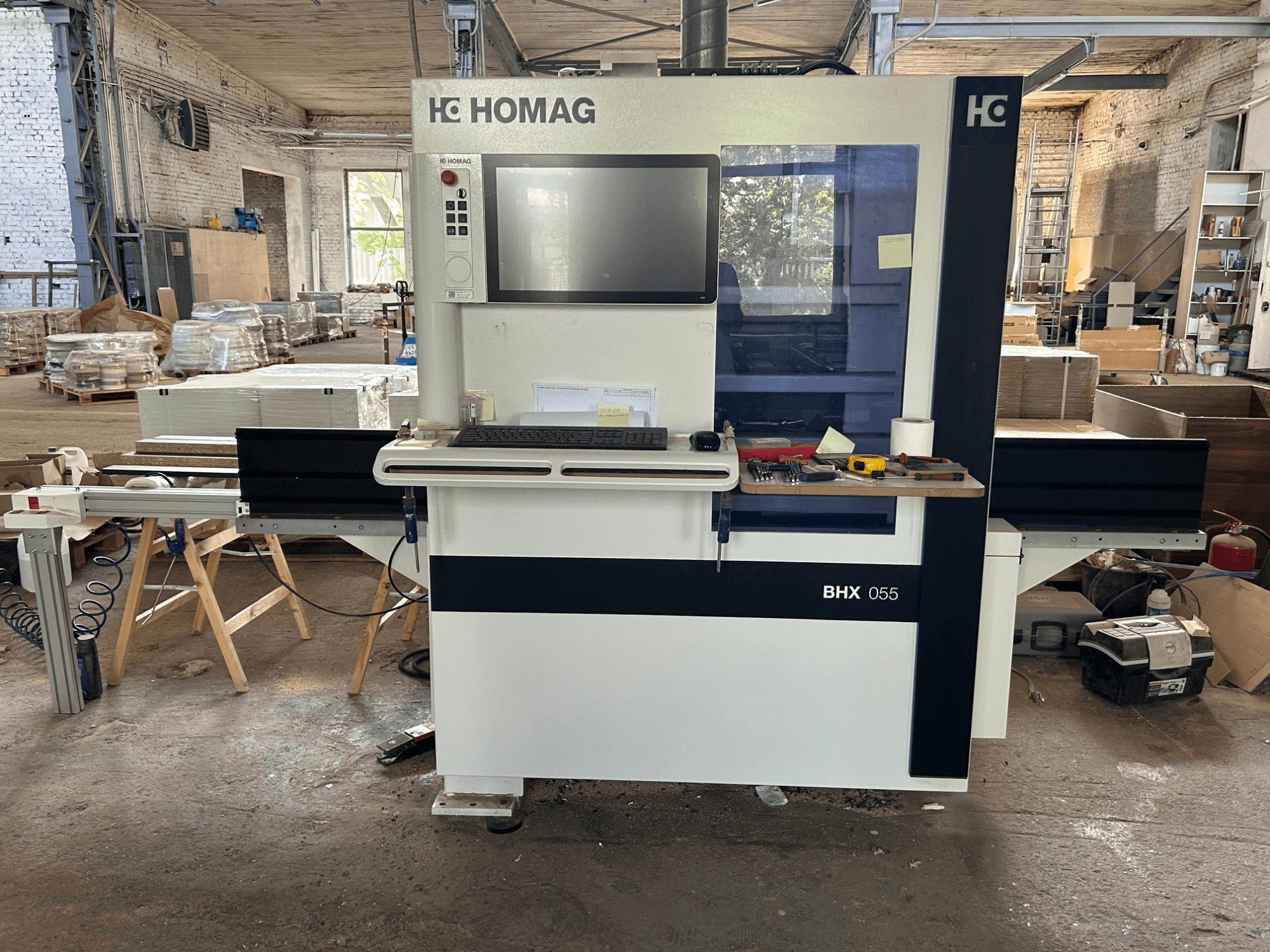 HOMAG WEEKE OPTIMAT BHX 055 CNC megmunkáló központ, elölnézet, a vezérlőpanellel és a szerszámokkal ellátott munkaterülettel.