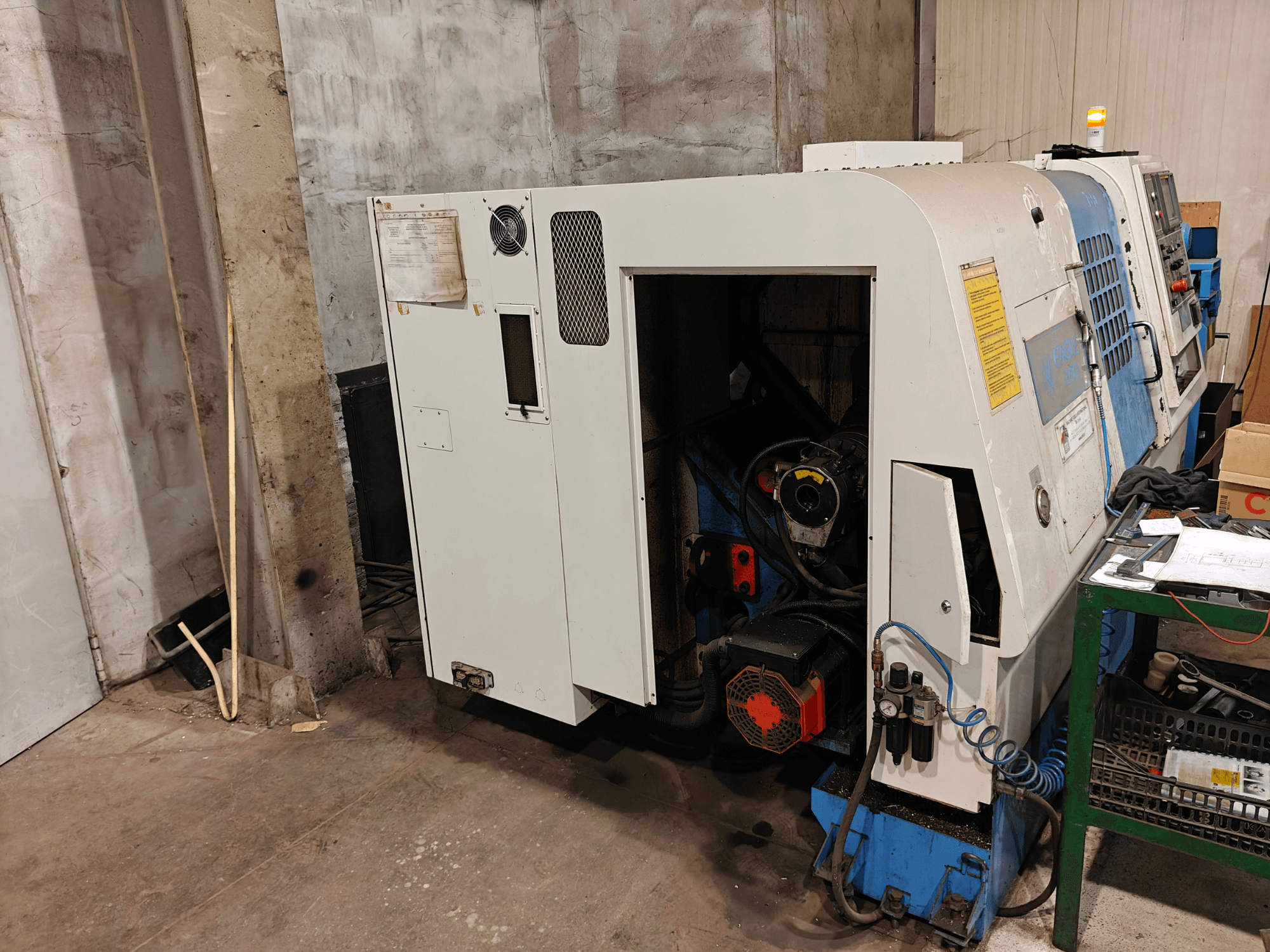 Egy esztergagép elülső nézete, márka és modell nincs meghatározva, vezérlőelemekkel és látható motorelemekkel.