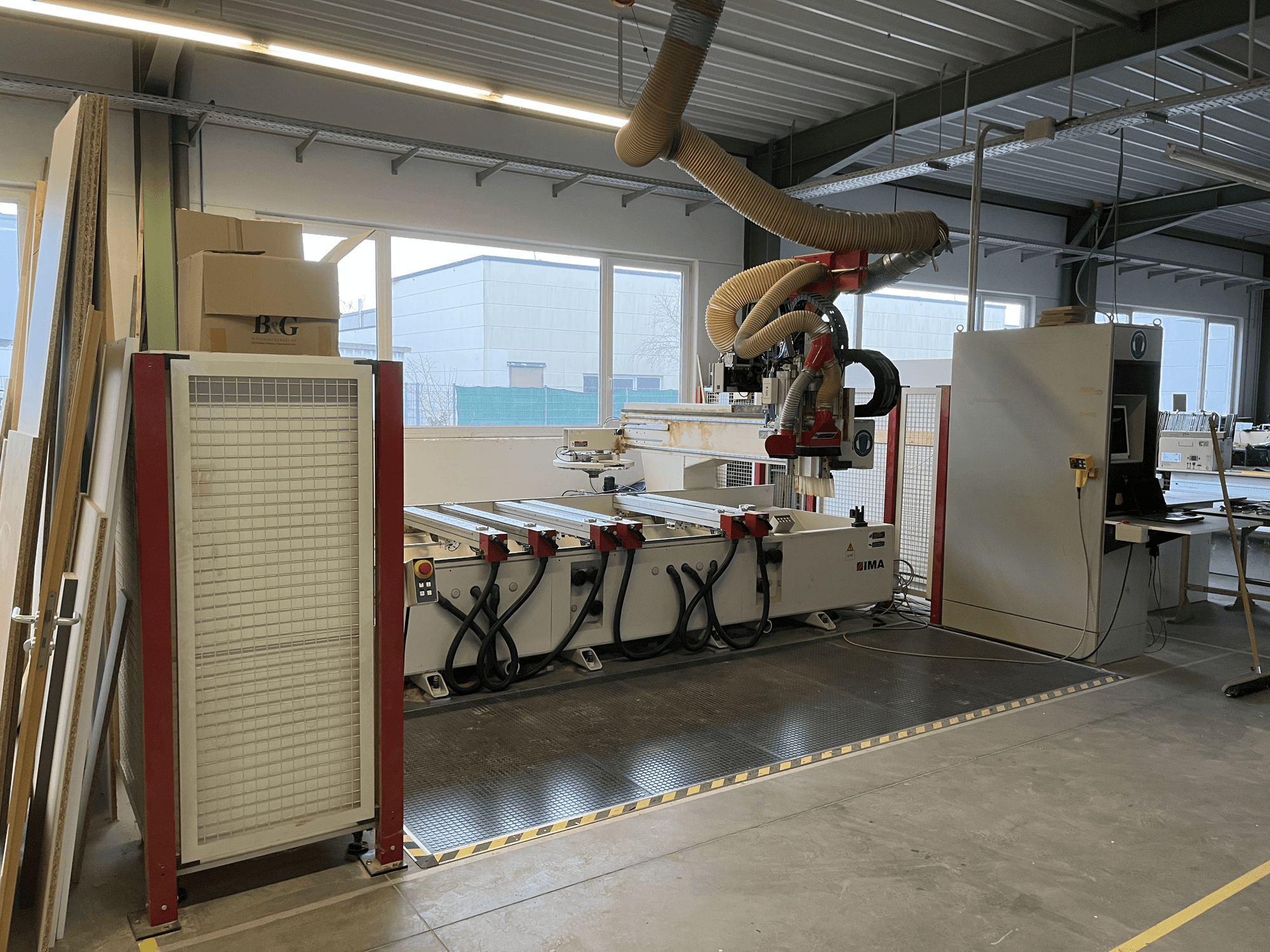 CNC faipari megmunkálóközpont IMA BIMA 410 a műhelyben, oldalnézet a kezelőpanellel és a porelszívó rendszerrel.