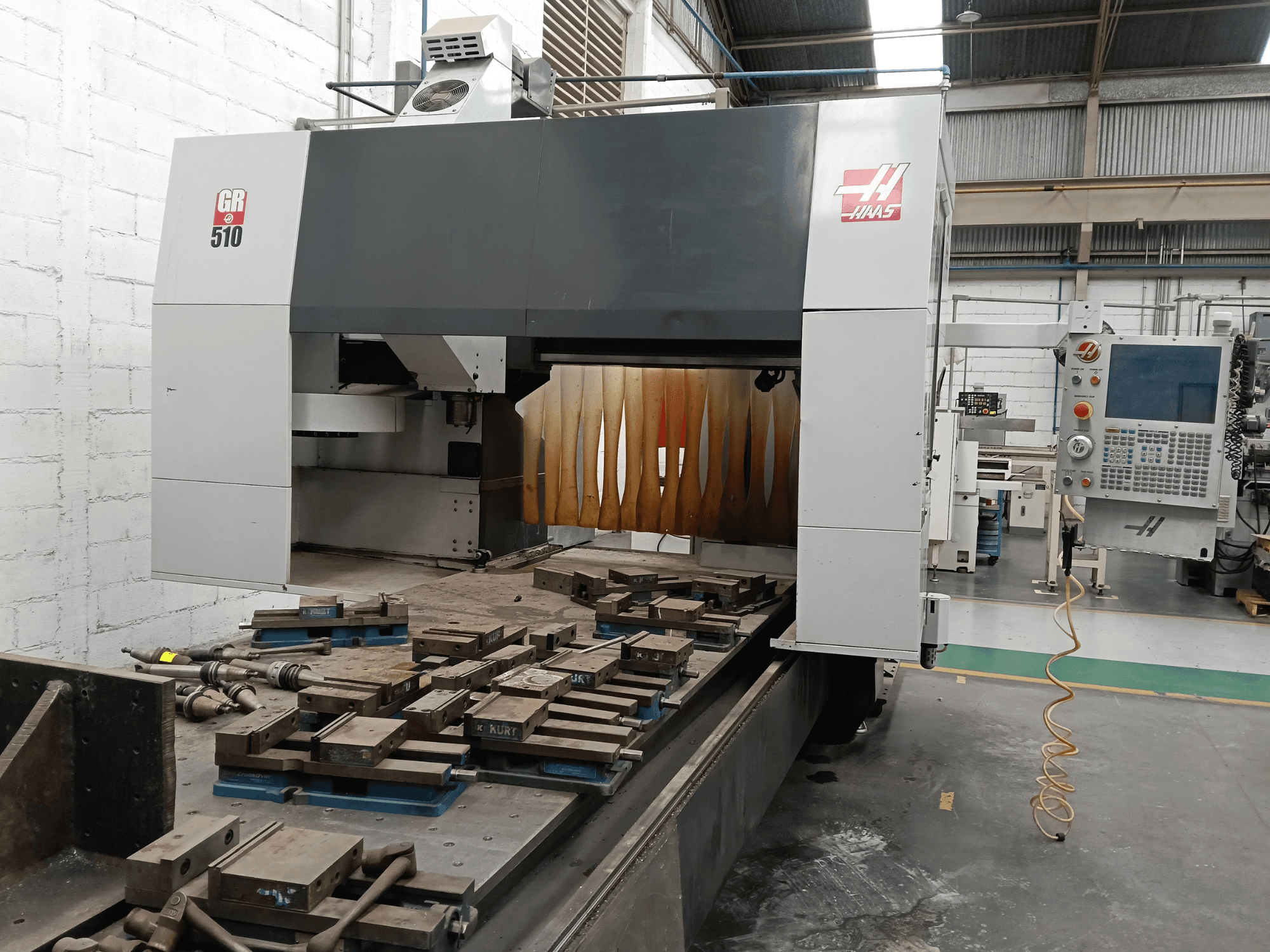 A HAAS GR-510 portálmarógép elölnézete, amelyen látható a vezérlőpanel és az asztalon elhelyezett megmunkált munkadarabok.