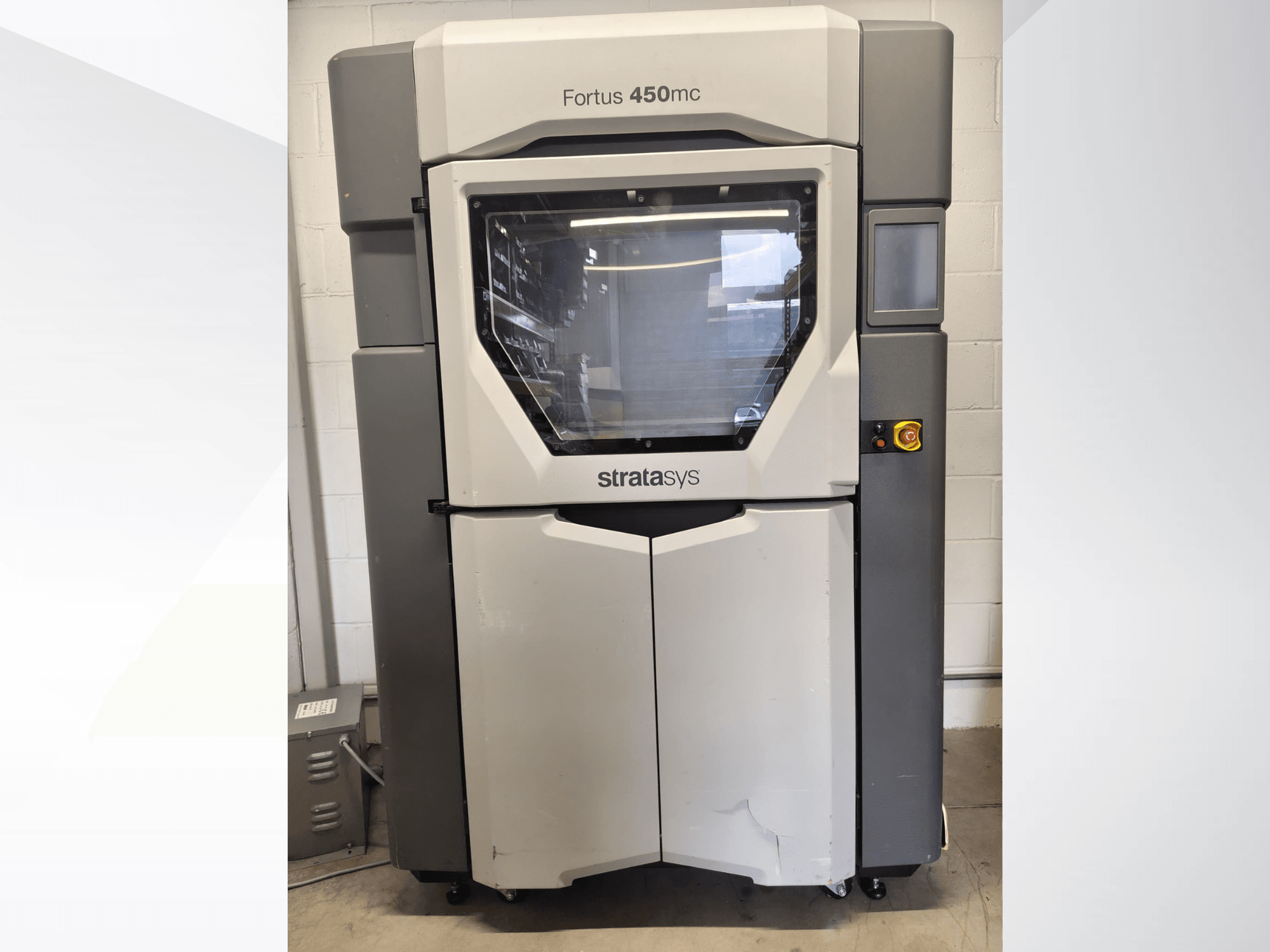 Stratasys Fortus 450mc műanyag-megmunkáló gép, elölnézet, nagy ablakkal, vezérlőpanellel és ipari formatervezéssel.