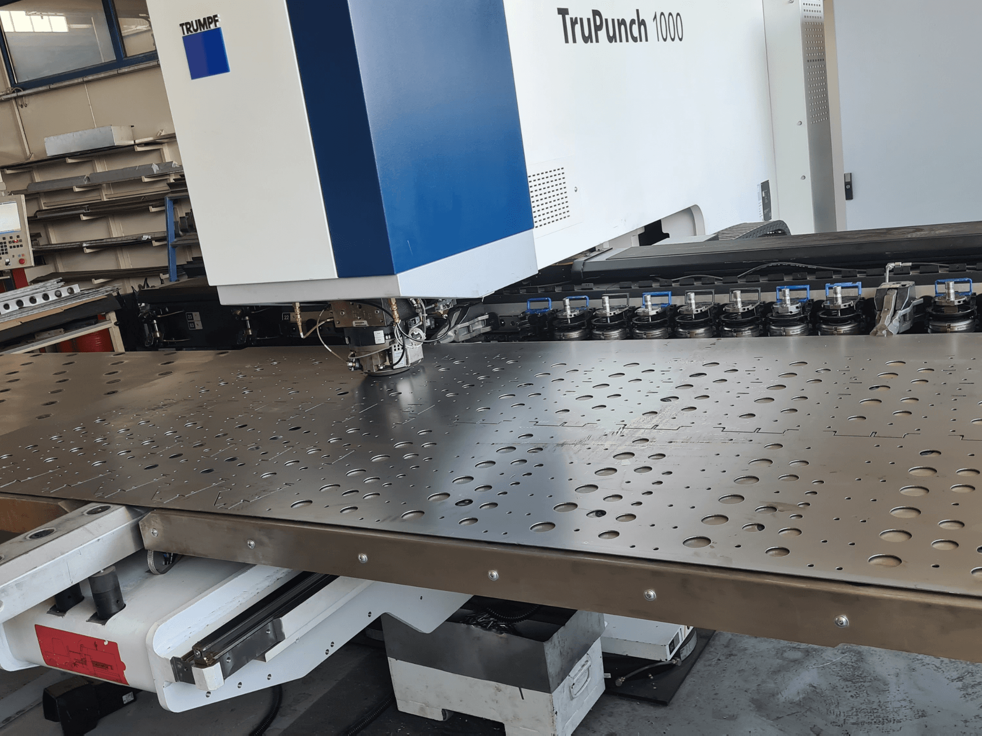 TRUMPF TruPunch 1000 CNC-lyukasztógép, elölnézet, perforált fémlemez és szerszámbeállítás látható.