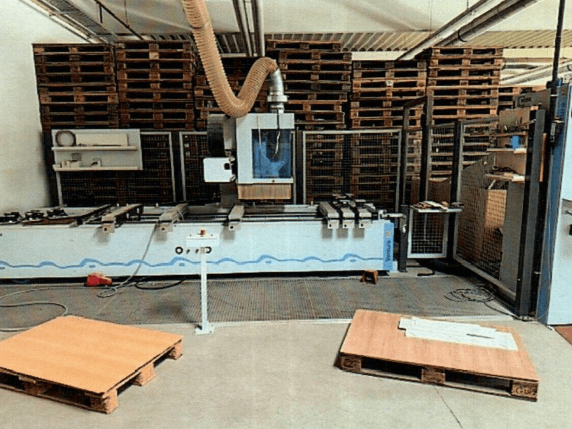 CNC faipari megmunkálóközpont Weeke Venture 1M egy műhelyben, elölnézetben, látható fa raklapokkal és ipari beállításokkal.