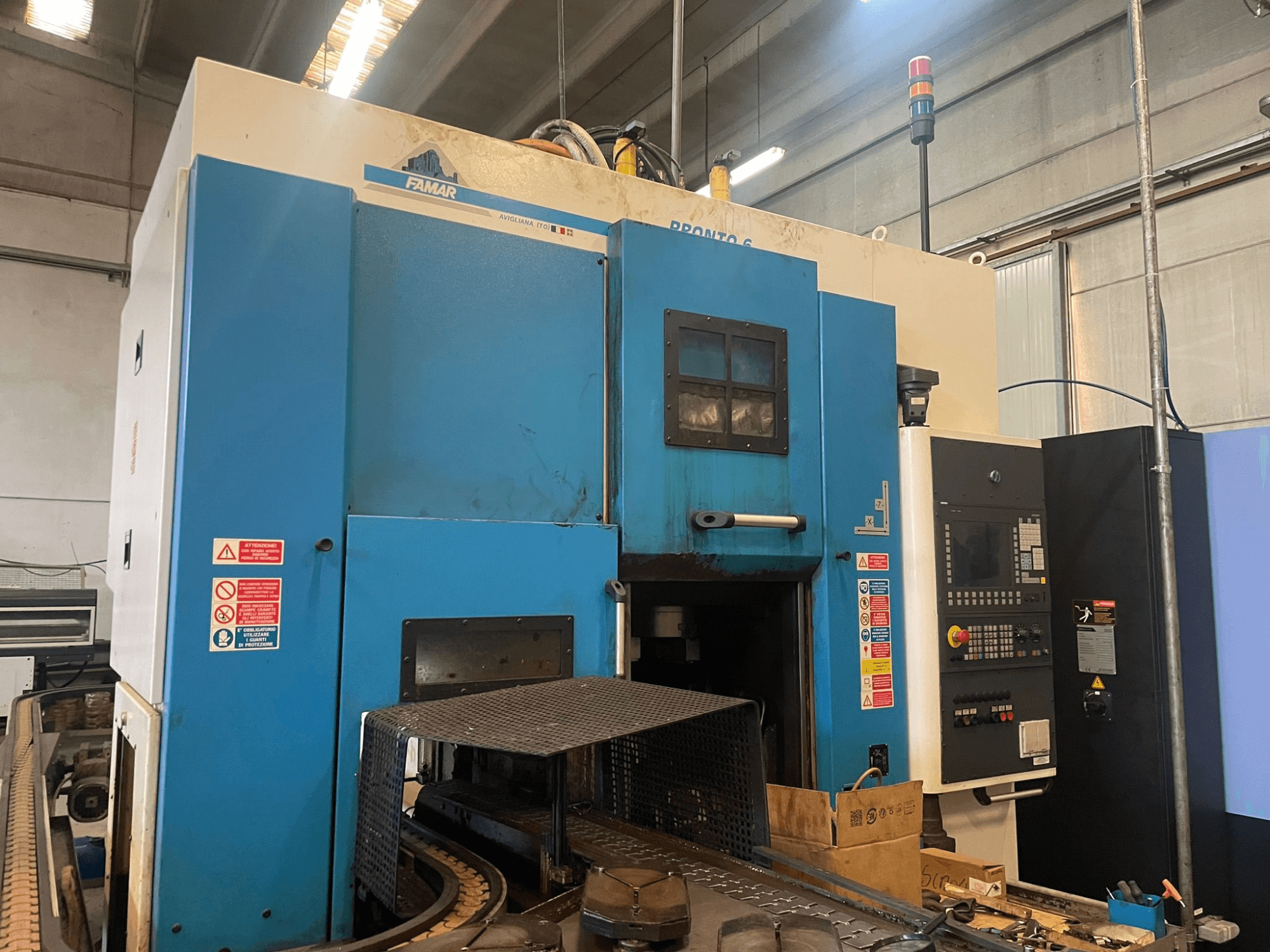 Famar Pronto 6 függőleges esztergagép egy műhelyben, oldalnézet, a kezelőpanel, a működési jellemzők és a biztonsági címkék láthatóak.