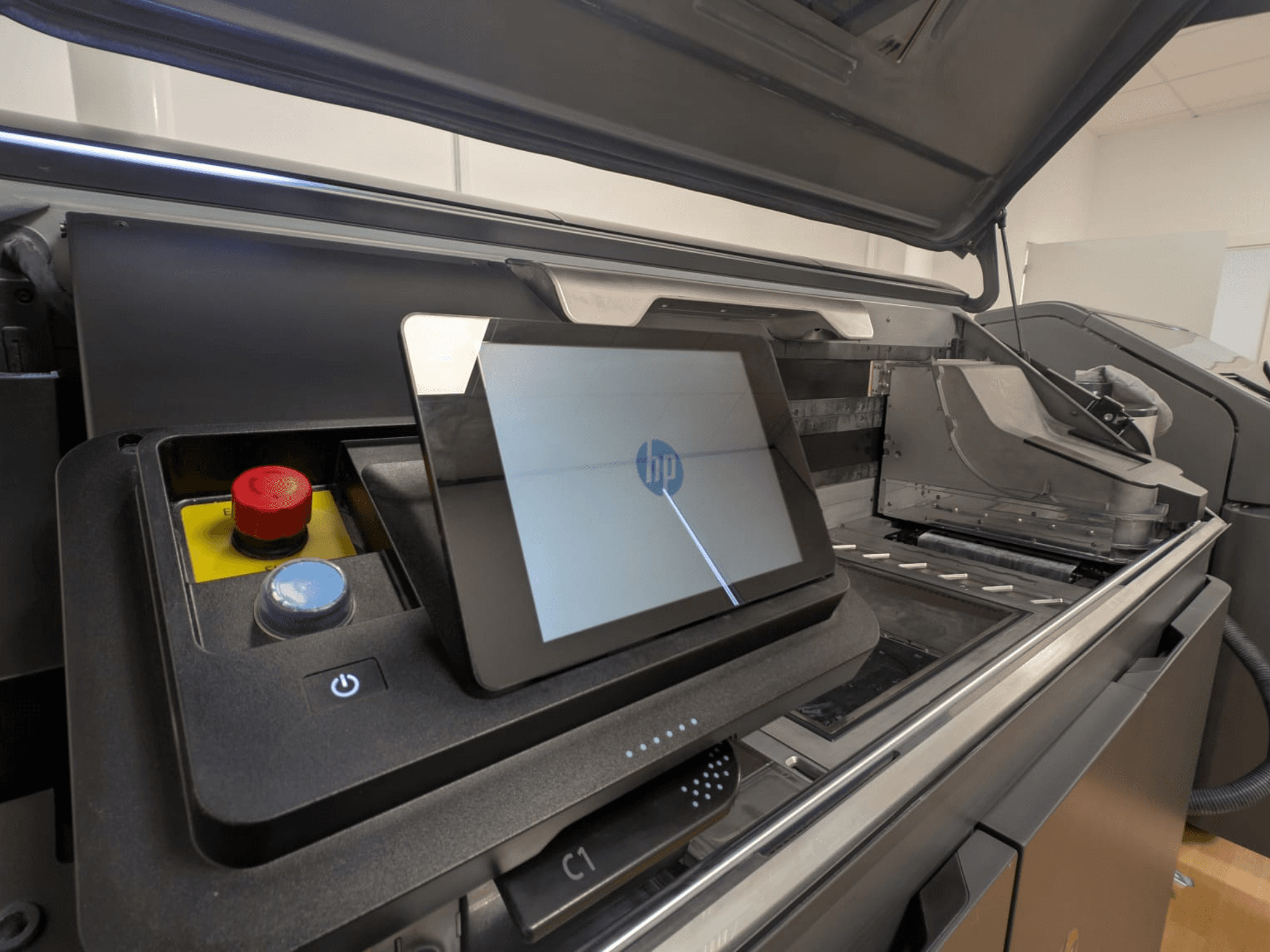 HP nyomtató vezérlőpanelje, amelyen a táblagép kijelzője, a piros és kék gombok, valamint a nyomtató belső alkatrészeinek oldalnézetben történő megjelenítése látható.