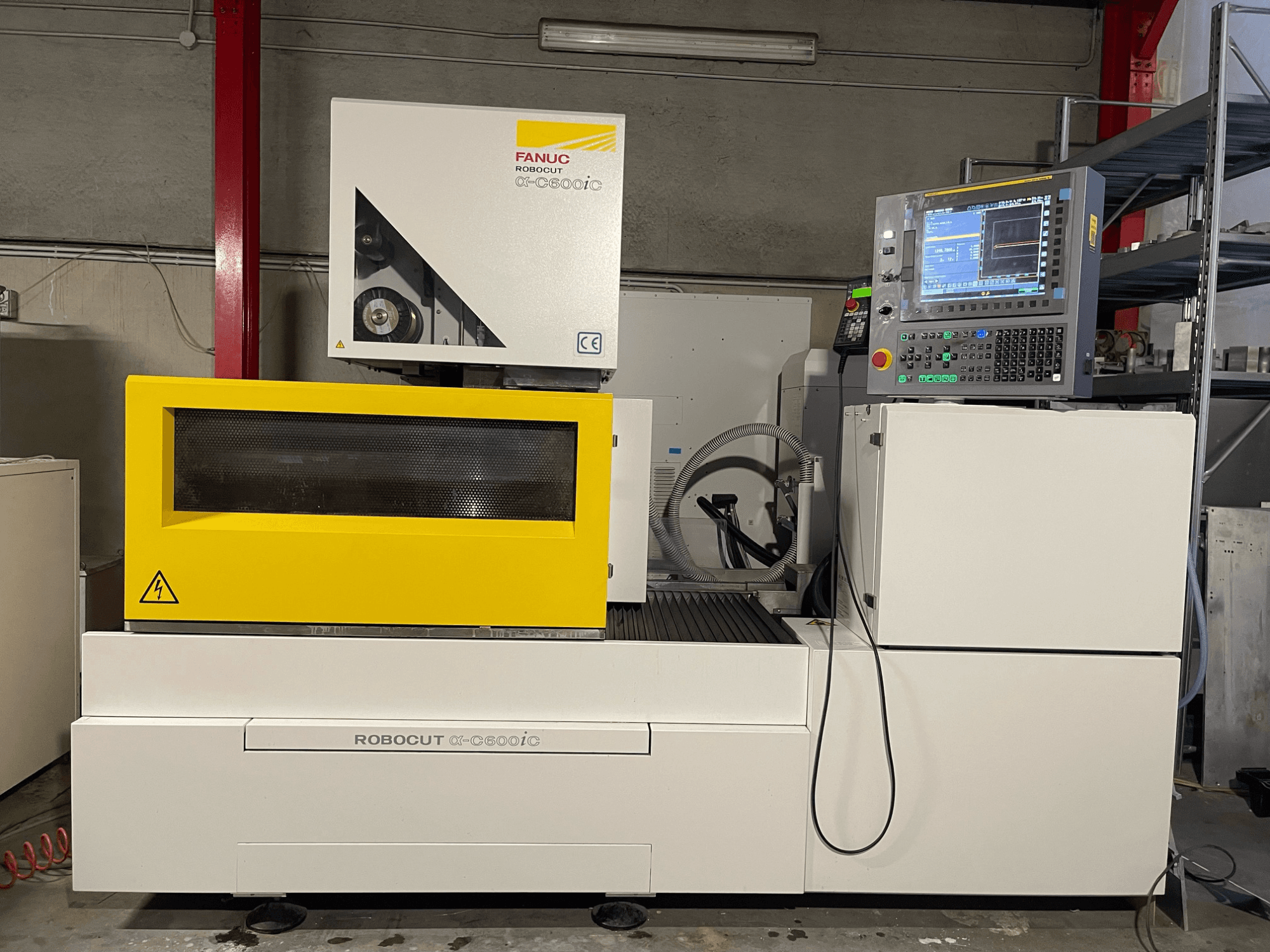 FANUC Robocut α-C600iC, a CNC-gép oldalnézetben, sárga biztonsági burkolattal és vezérlőpanellel, a precíziós vágási képességet bemutató CNC-gép.
