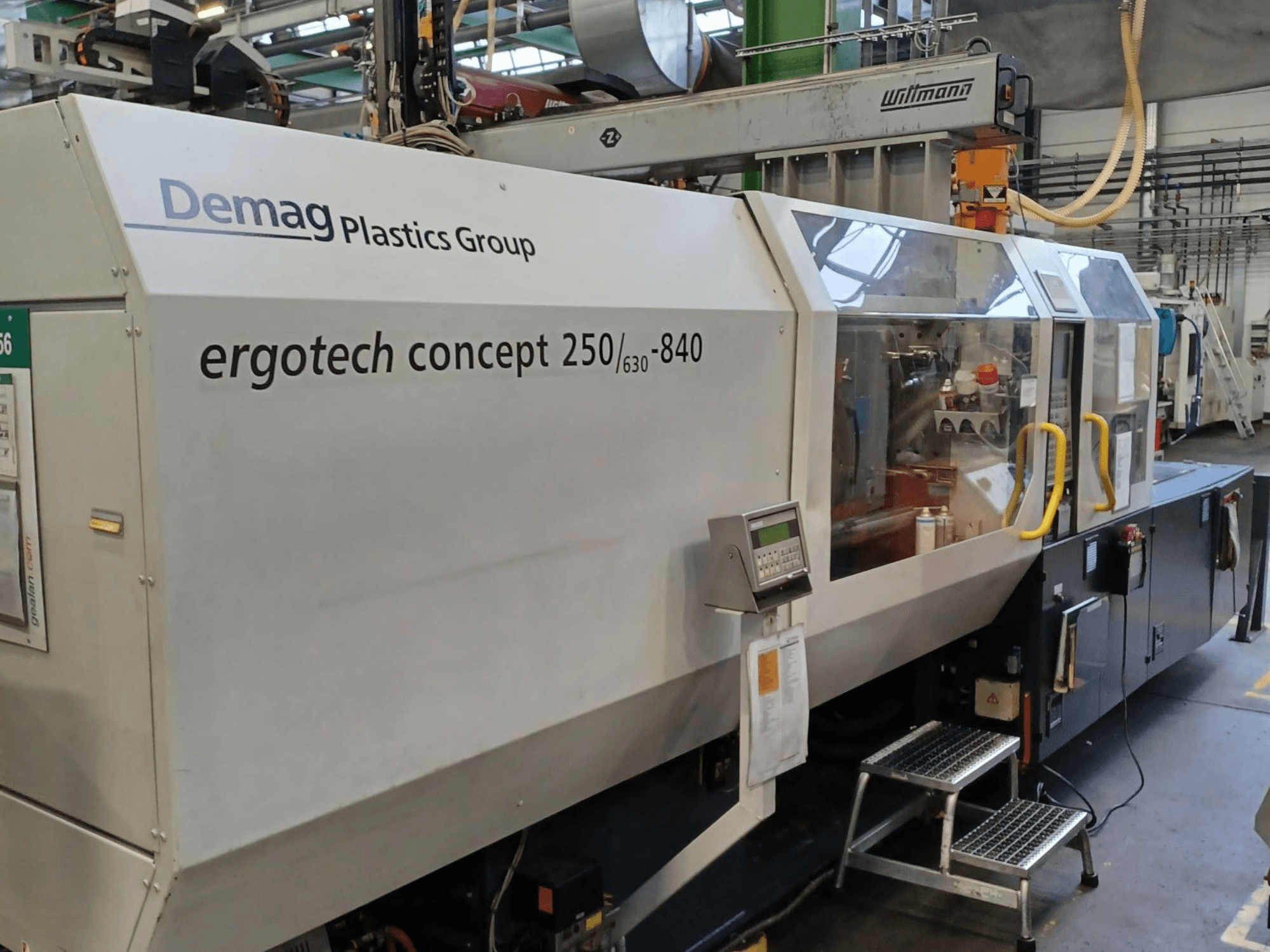 Demag ergotech concept 250/630-840 fröccsöntőgép, előlnézet, digitális vezérlőelemek és átlátszó biztonsági burkolatok.
