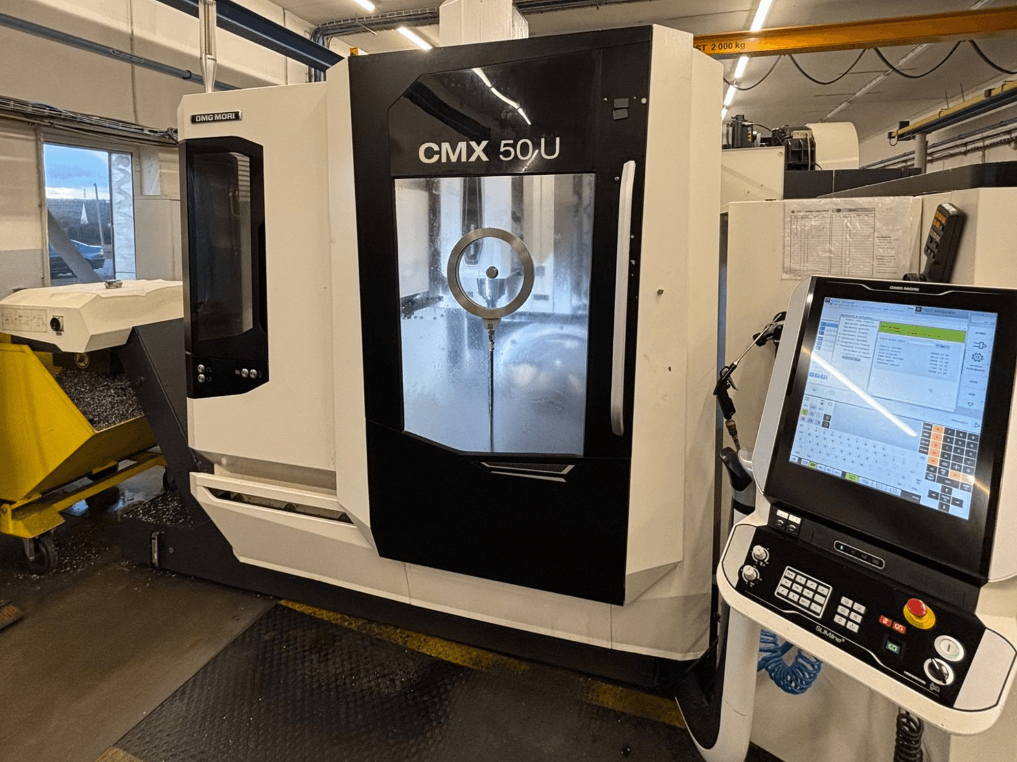 DMG MORI CMX 50 U függőleges megmunkálóközpont, előlnézet a vezérlőpanellel és az üveg kijelzővel, a belső mechanika bemutatásával.