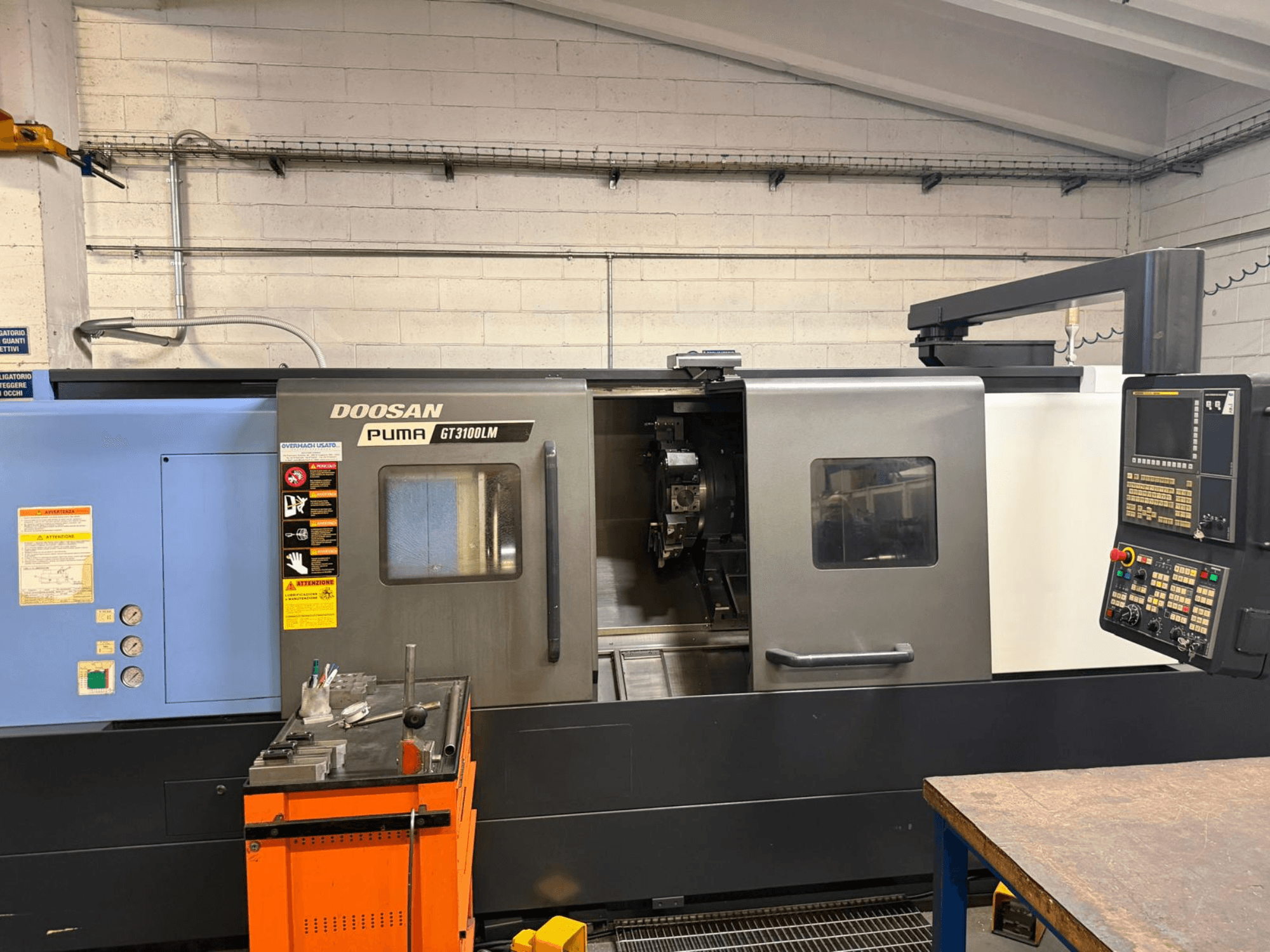 A DOOSAN PUMA GT3100LM vízszintes esztergagép elülső nézete, a vezérlőpanel és a szerszámokkal ellátott munkaterület bemutatása.