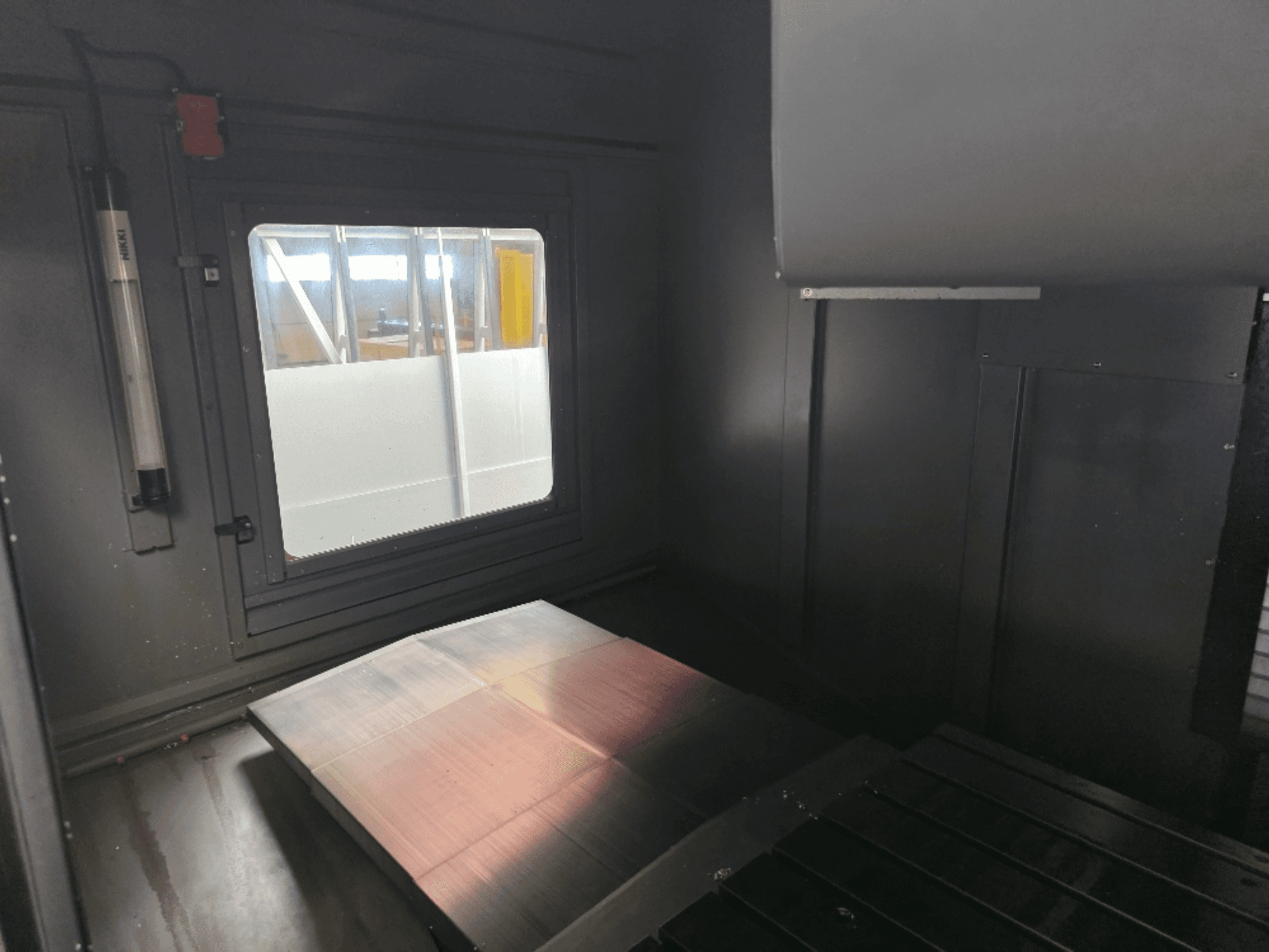 Egy gépház belső nézete polírozott fémlemezzel, oldalablakkal és minimális világítással. Márka nem látható.