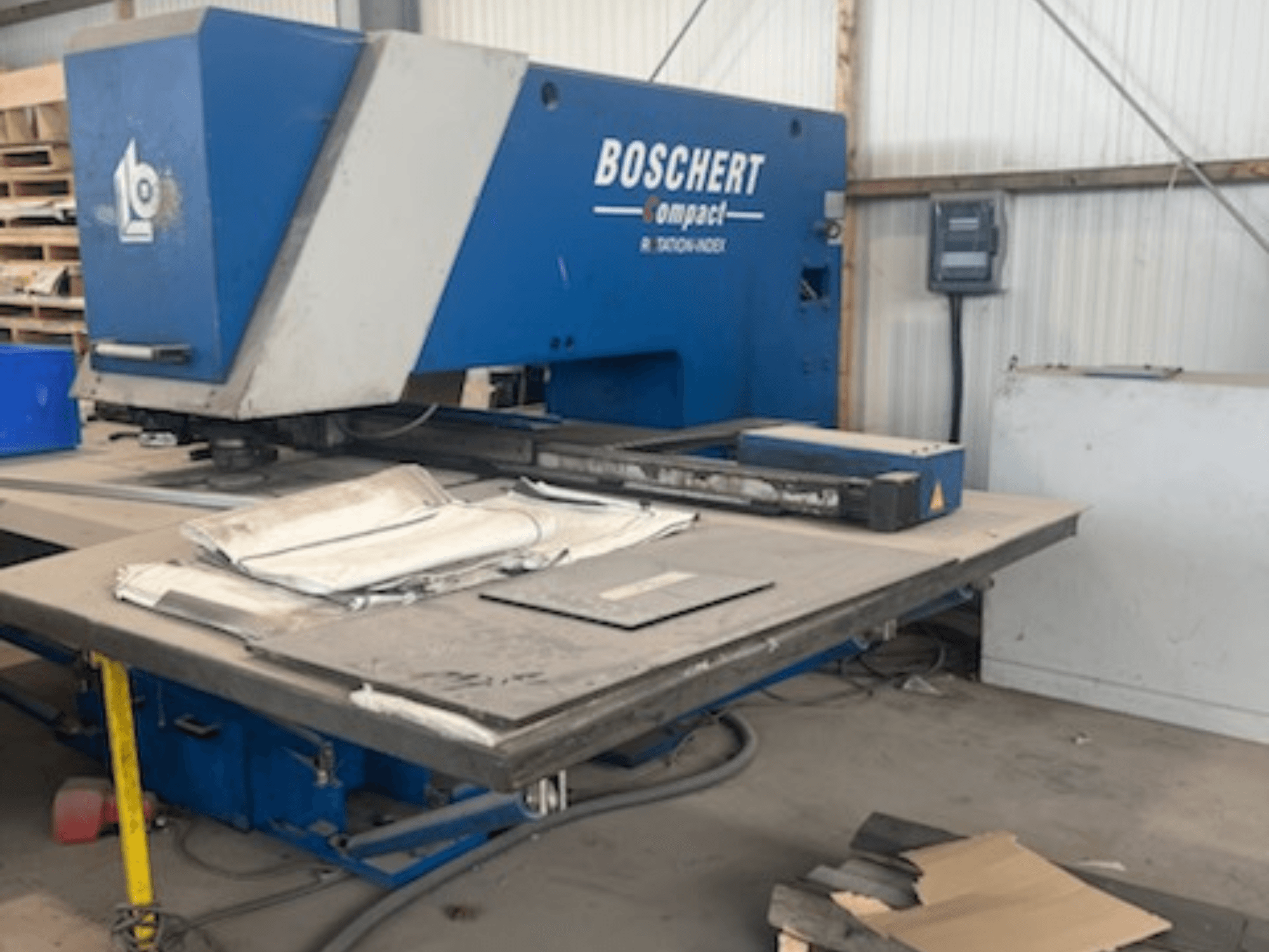 Egy műhelyben álló BOSCHERT COMPACT 1000 CNC lyukasztógép, elölnézetből, a munkaasztalon fekvő fémlemezekkel.