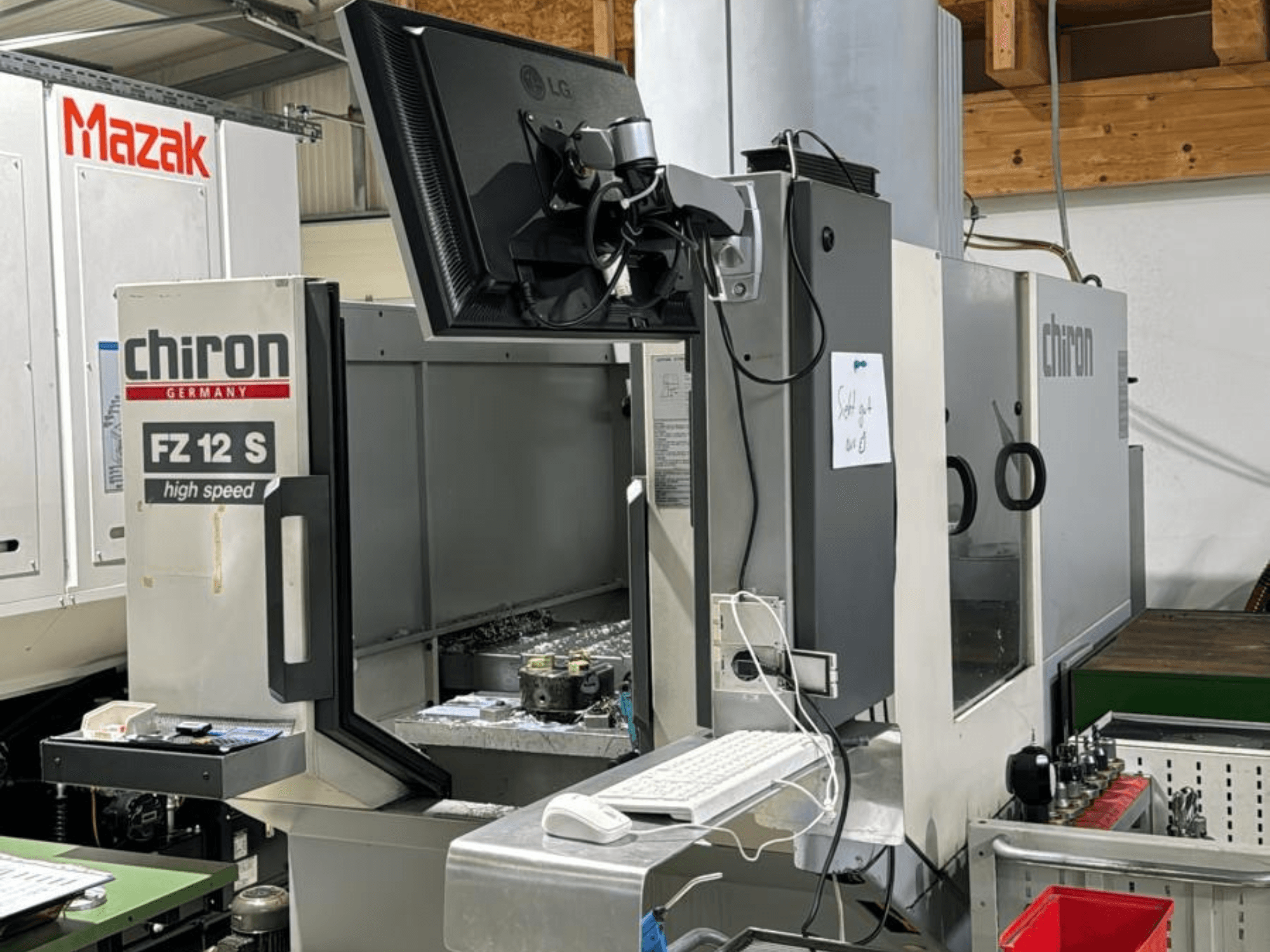 A CHIRON FZ 12 S nagysebességű megmunkálóközpont függőleges nézete a vezérlőképernyővel és a megmunkálásból származó törmelékkel.