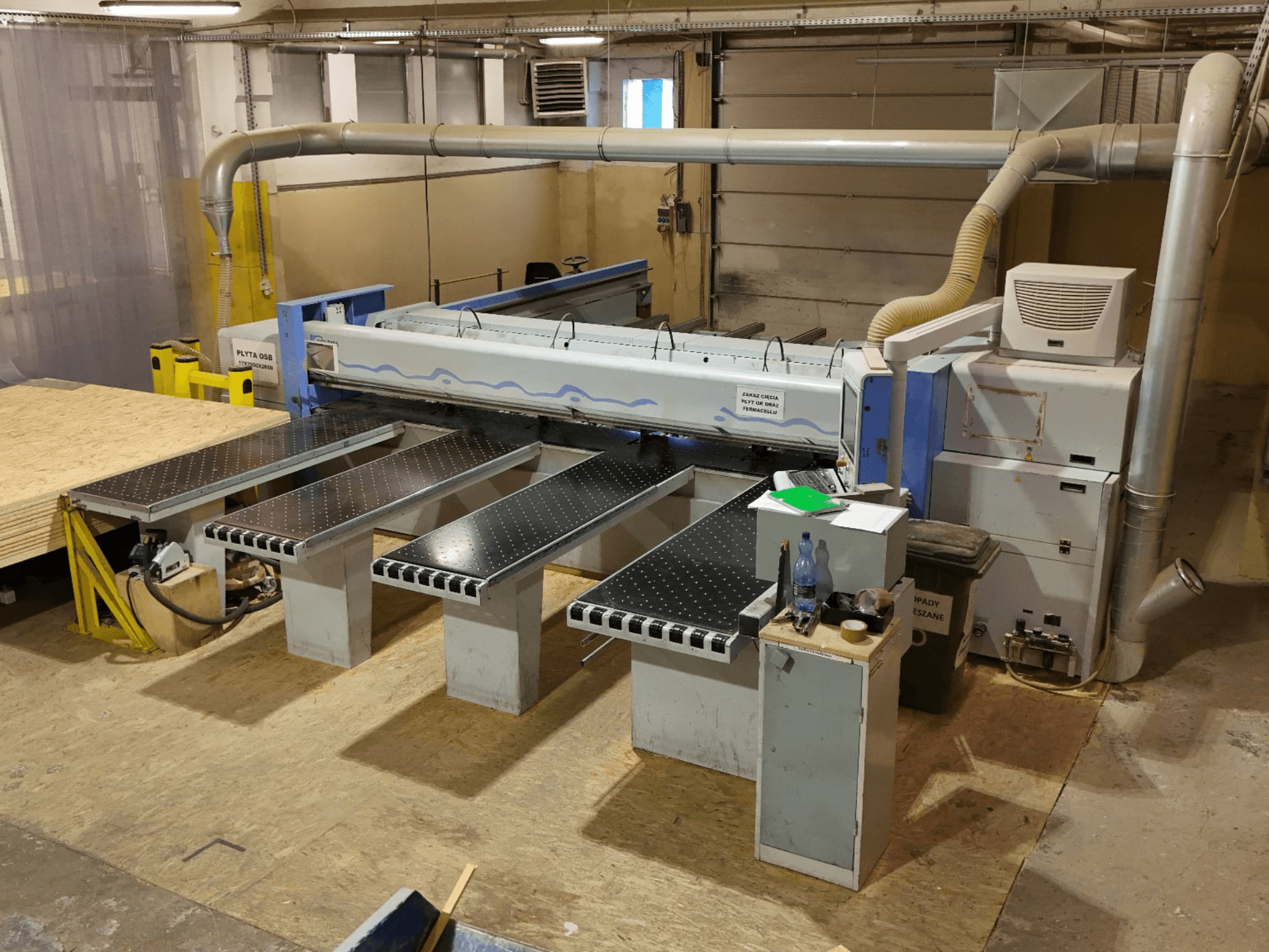 HOLZMA HPP 350/43/38 lemezfűrész egy műhelyben, felülnézetből, a vágási területtel és a támasztóasztalokkal.