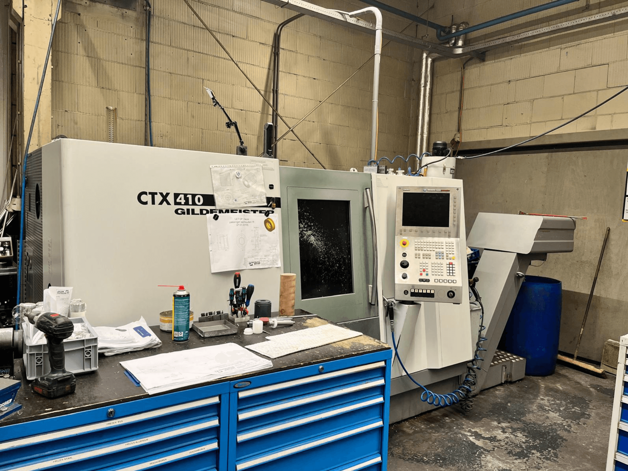 Gildemeister CTX 410 CNC-gép egy műhelyben, elölnézetben, vezérlőpanel és különböző szerszámok a munkapadon.
