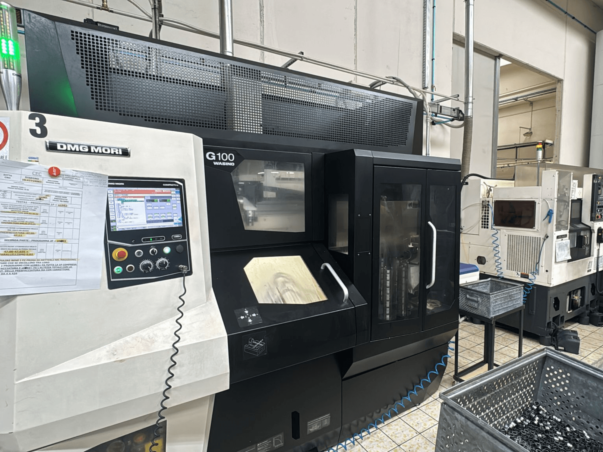 DMG MORI G100 gép egy gyárban, elölnézetben, digitális vezérlőpanellel és közeli szerszámtároló rekeszekkel.