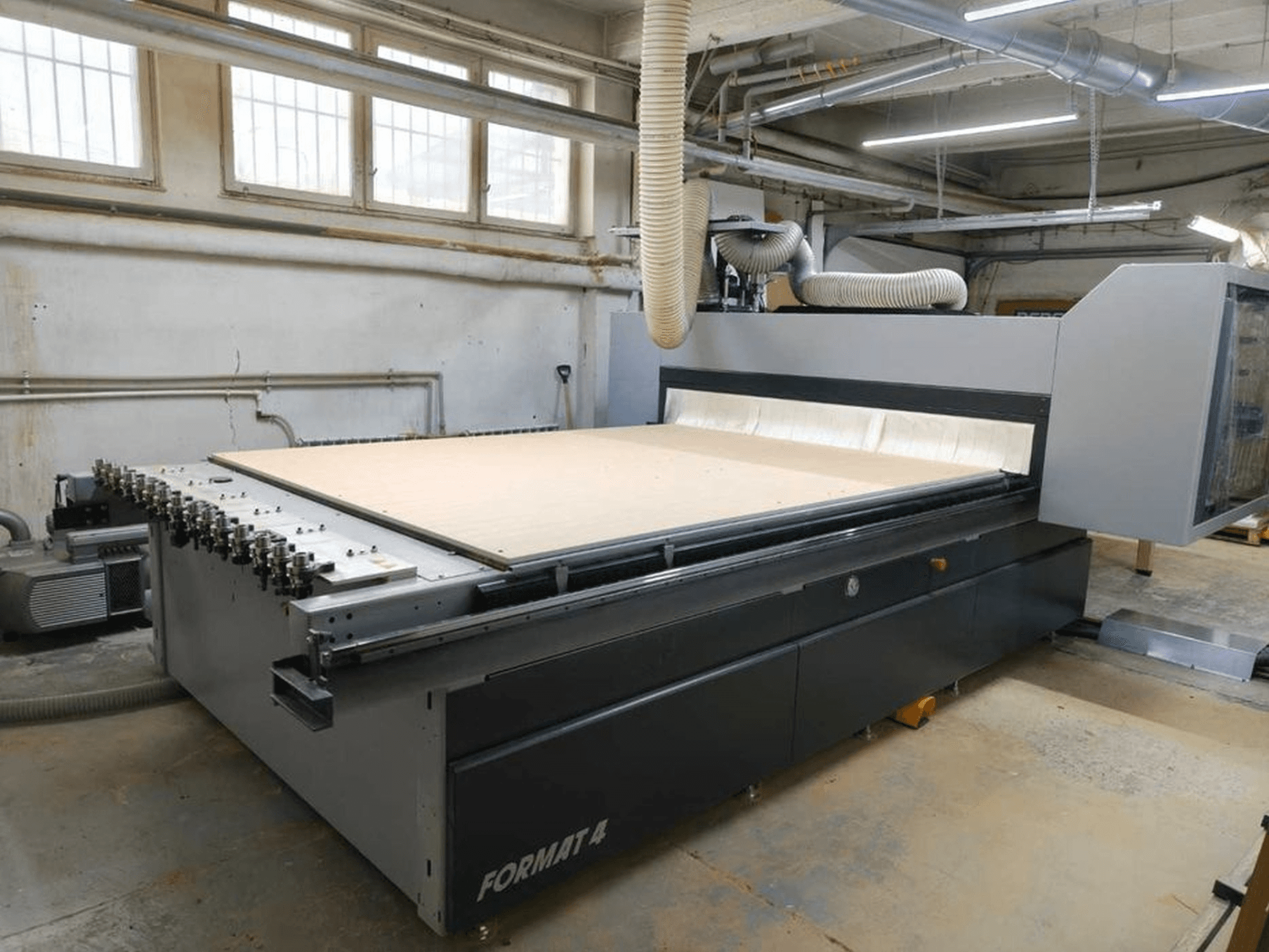 CNC Router FORMAT4 Profit H80 H80 21,31 műhelyben, oldalnézetben, nagy vágási felülettel és látható tömlővel a porelszíváshoz.