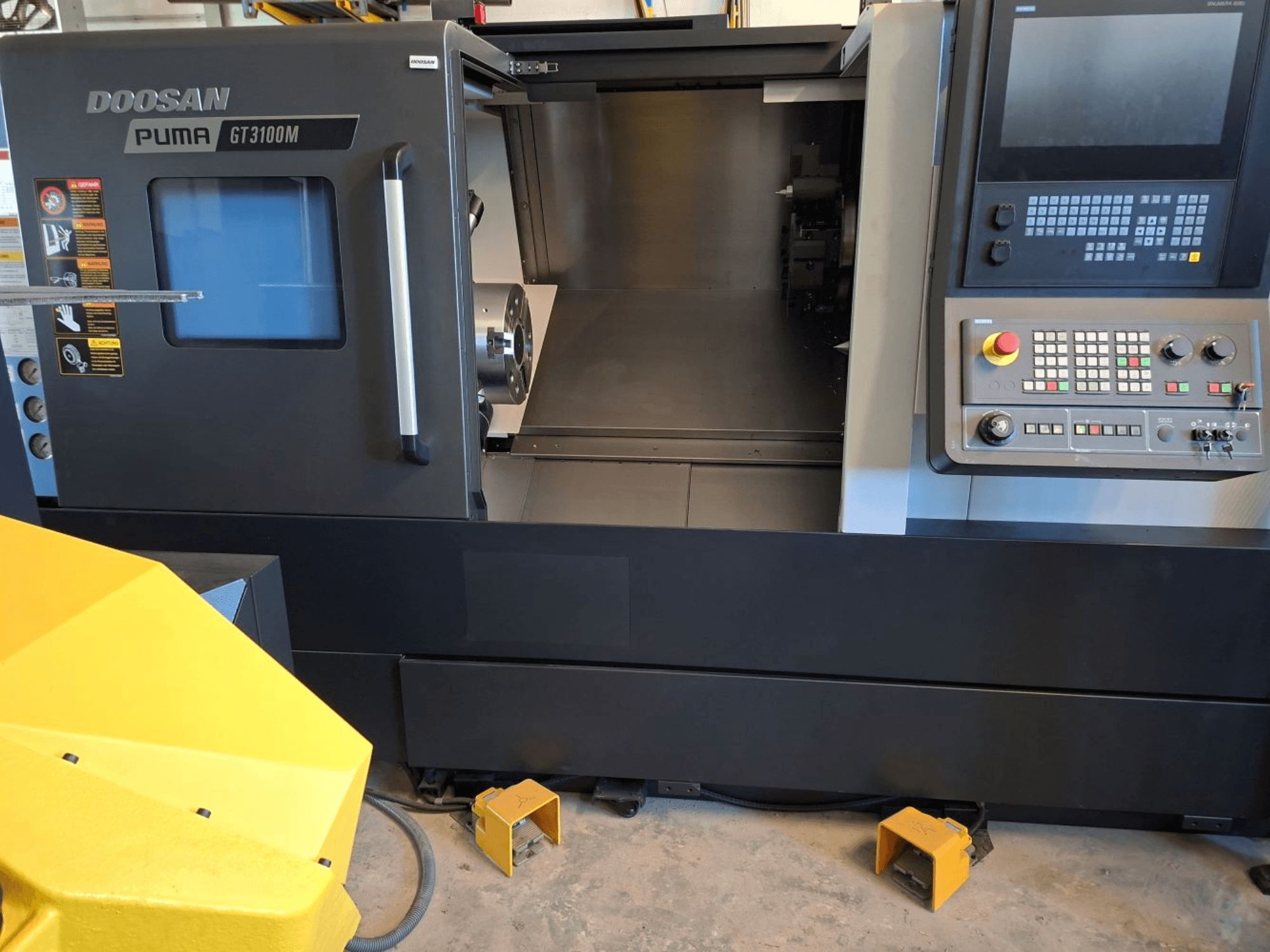 DOOSAN Puma GT 3100 M vízszintes esztergagép elölnézetben, a vezérlőpanel, a nyitott revolver és a belső munkaterület bemutatásával.