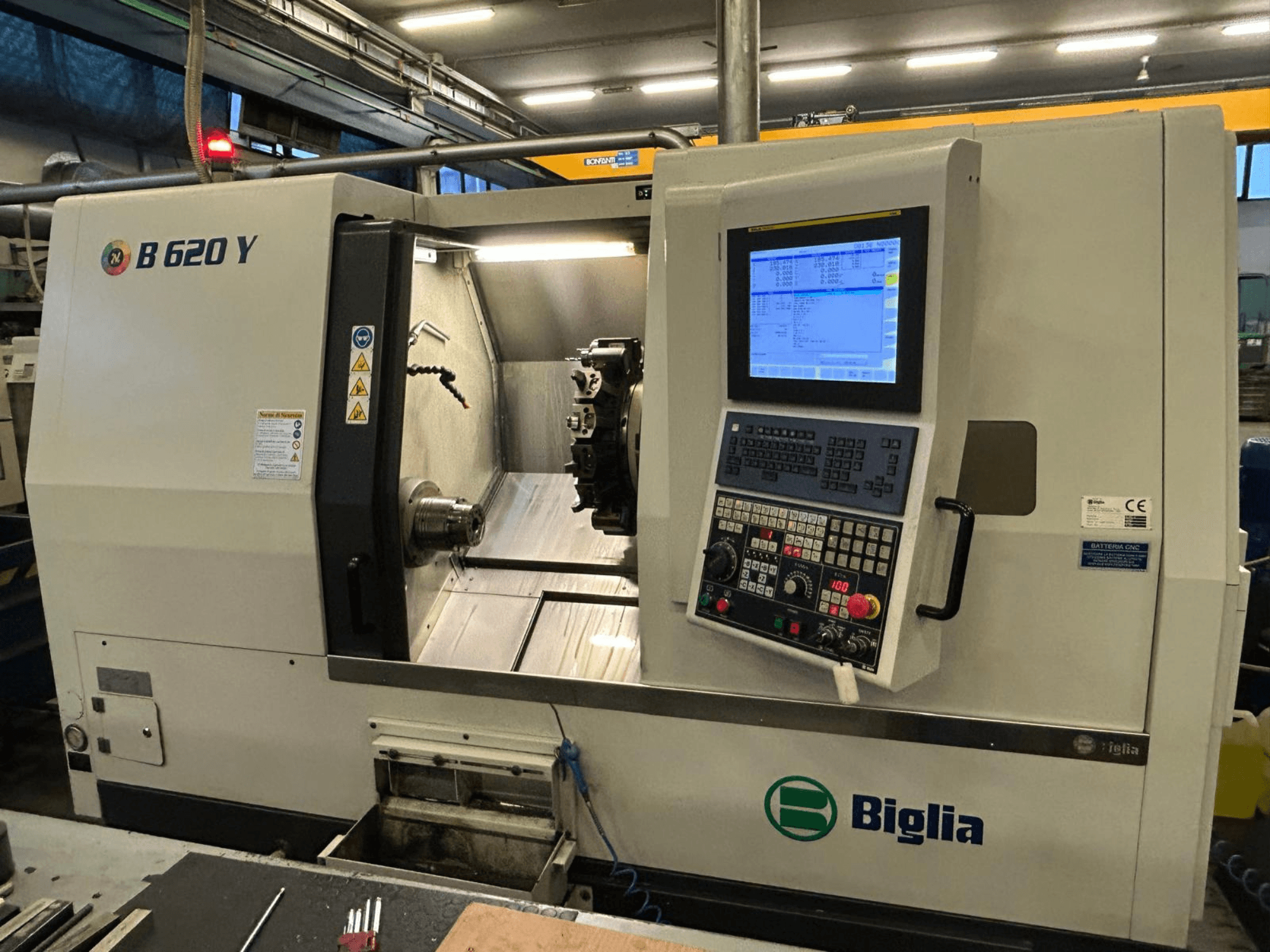 Biglia B 620 Y CNC esztergapad egy műhelyben, elölnézetben, a digitális kijelzővel ellátott vezérlőpanel és a megmunkáló alkatrészek.