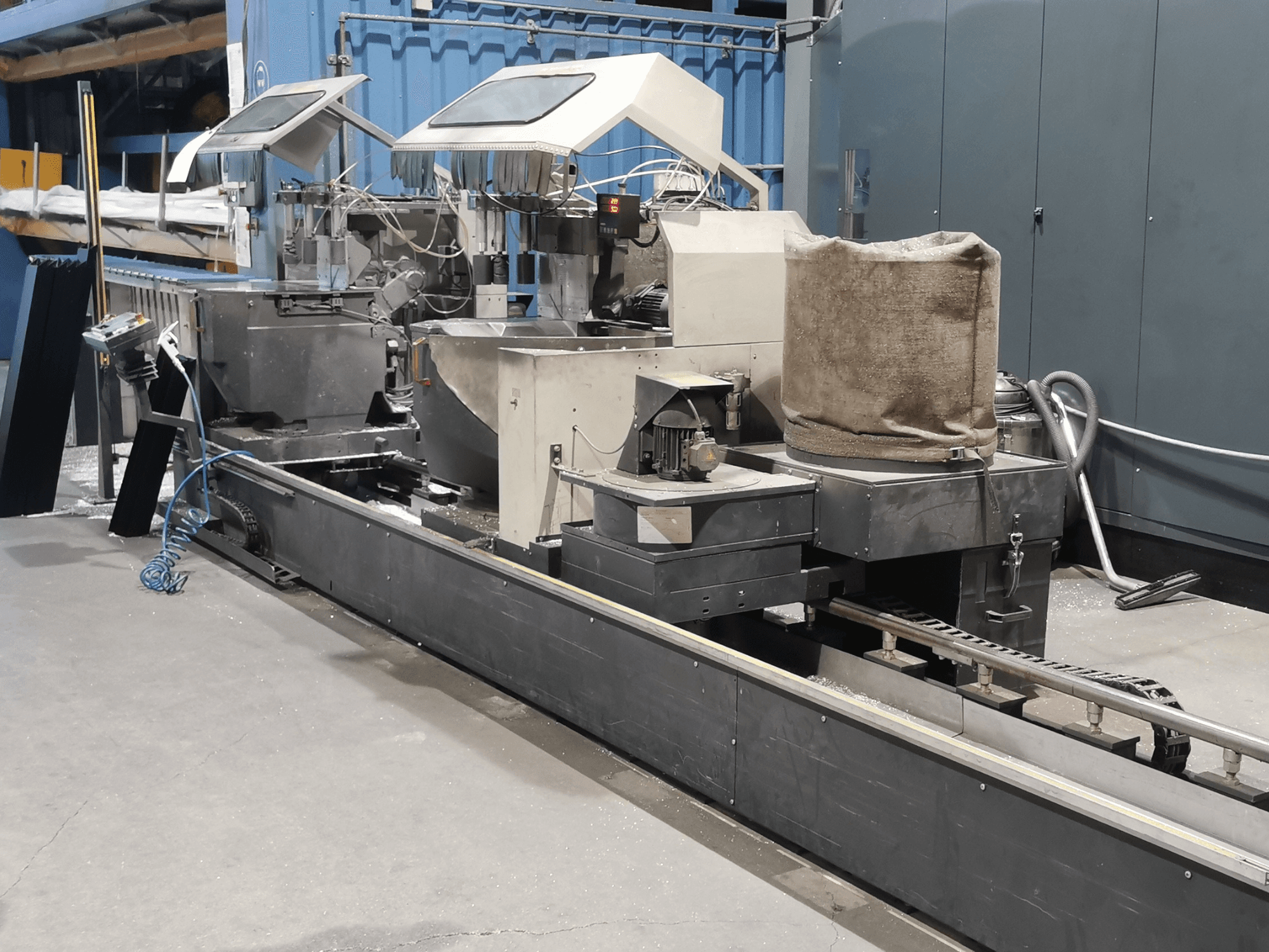 Ipari feldolgozógép oldalnézetből, tartályokkal, szállítószalaggal és vezérlőpanellel, gyári környezetben.