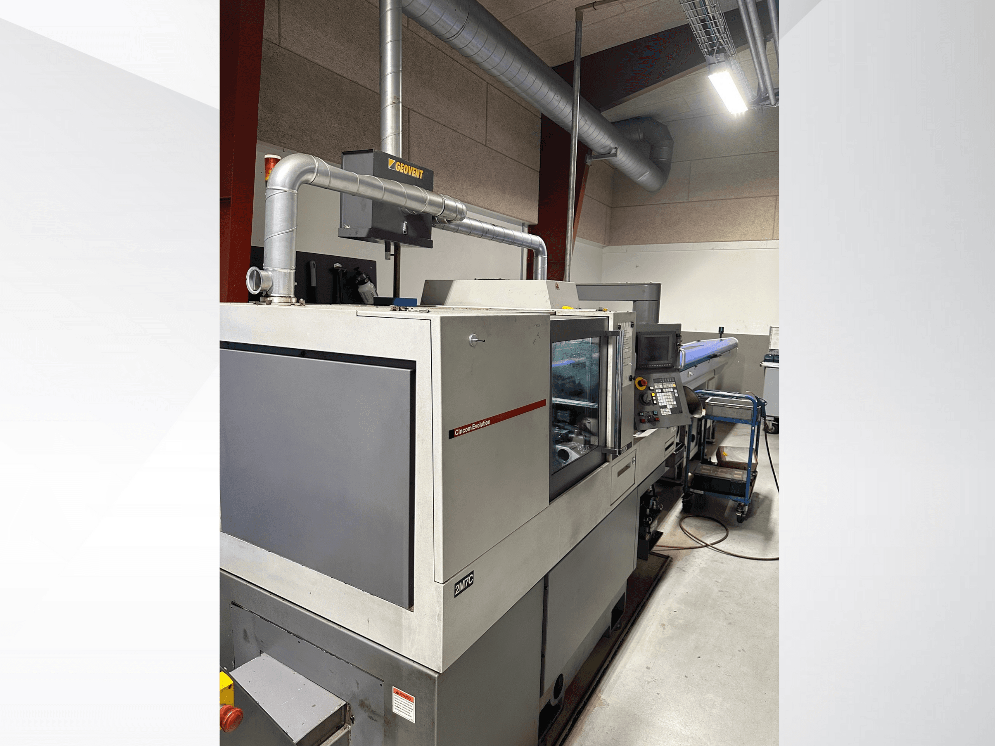 Ipari gép az MVC márkától, oldalnézet a vezérlőpult és a csatornarendszer látható, gyári környezetben.