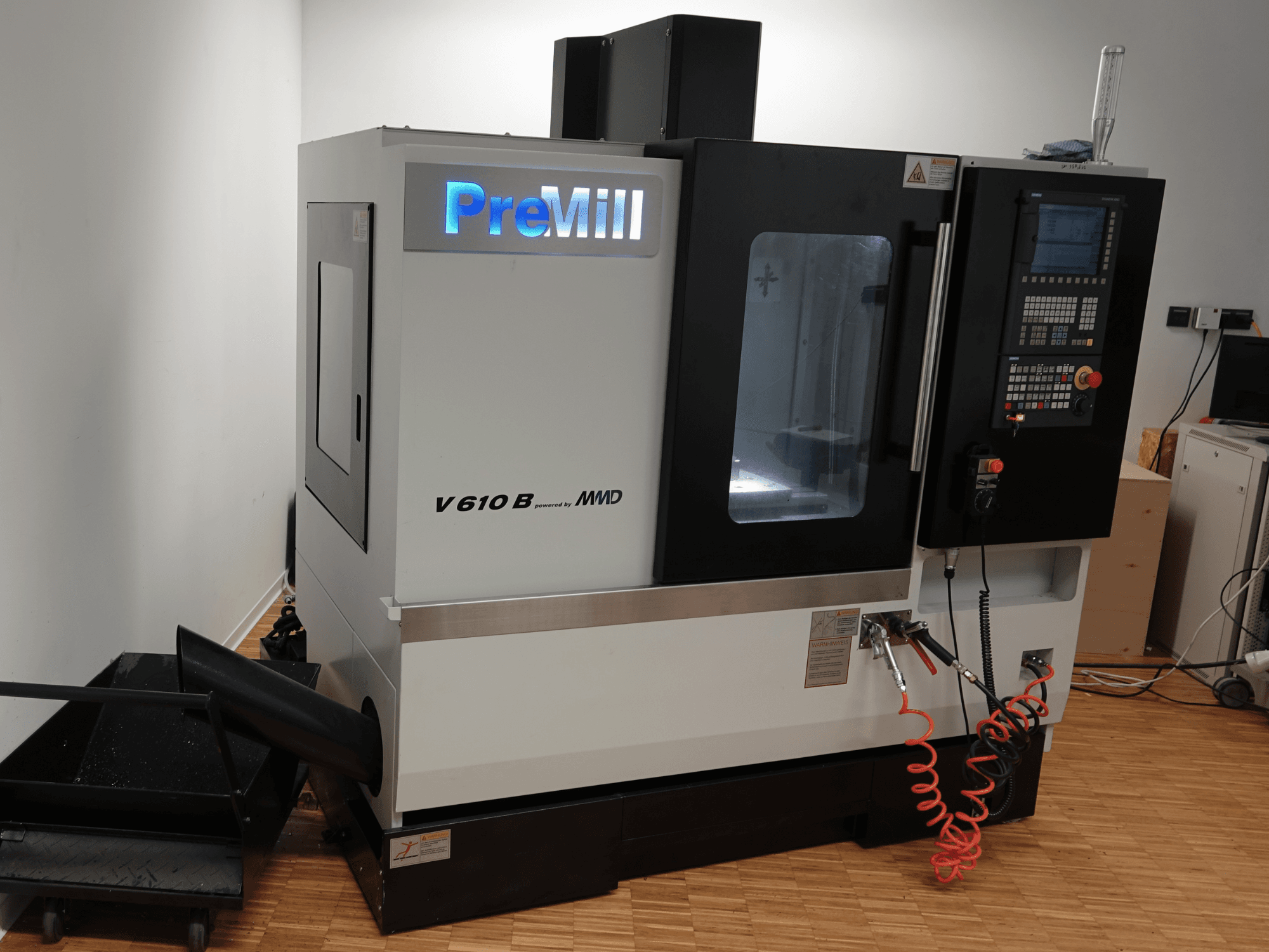 PreMill V 610 B függőleges megmunkáló központ, elölnézet, a vezérlőpanellel, a hűtőfolyadék-rendszerrel és a csatlakoztatott légtömlőkkel.