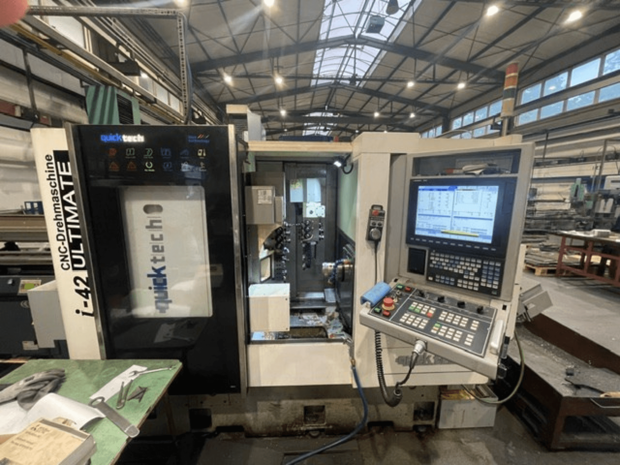 Quick-Tech I-42U svájci típusú esztergagép, előlnézet, a vezérlőpanel és a CNC-interfész műhelykörnyezetben.