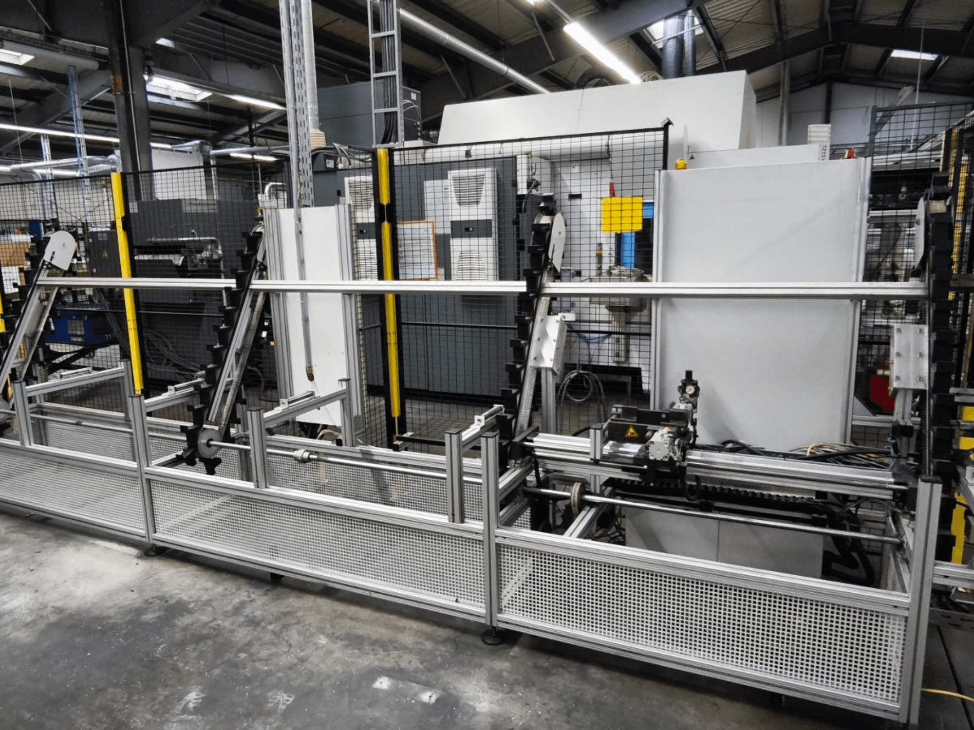 LOHMEIER Schräglademagazin munkadarab-kezelő rendszer elölnézetben, bemutatva a fémszerkezetet és a beépített mechanikai alkatrészeket.