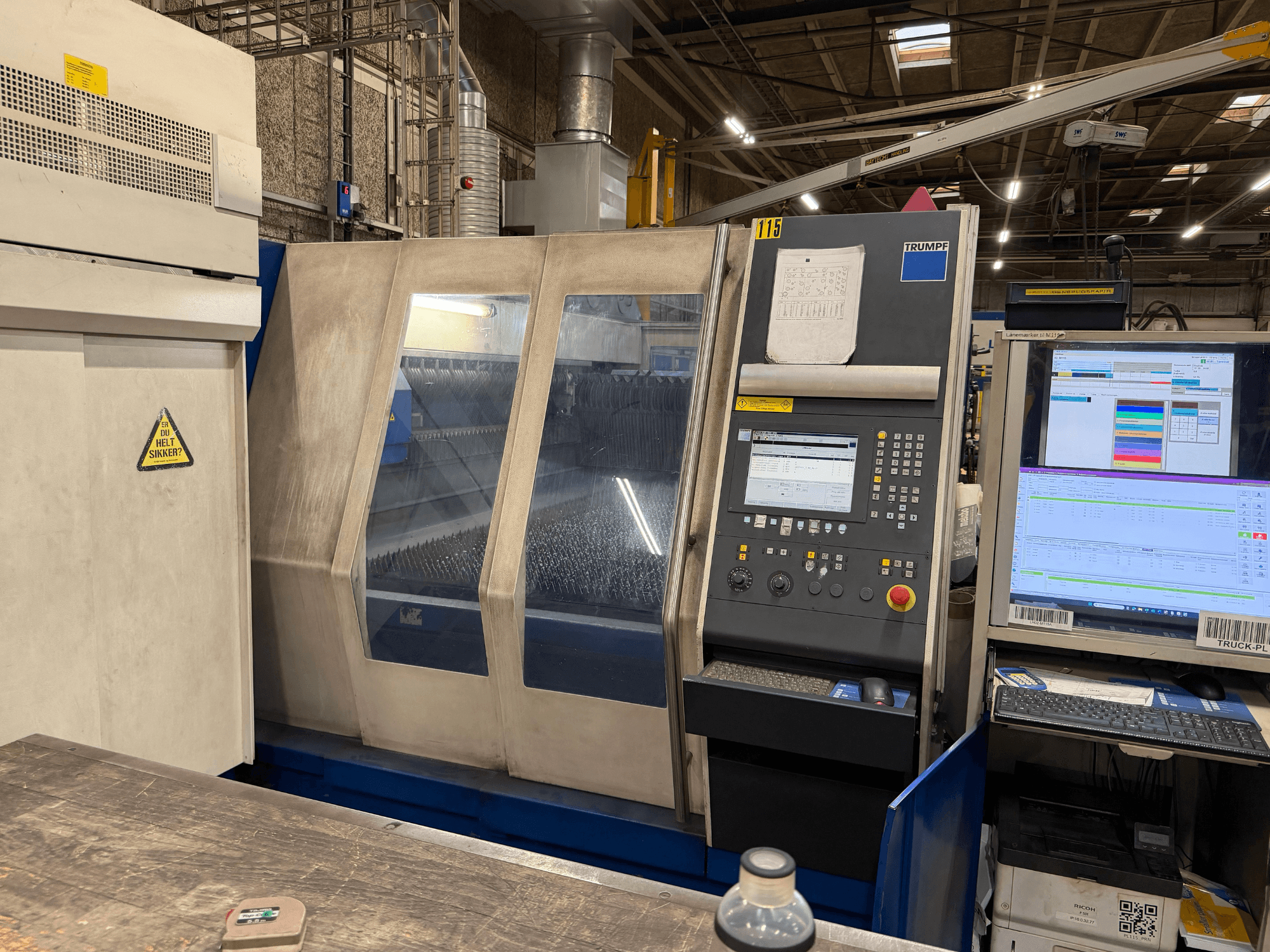 Egy Trumpf ipari lézergép előlnézetben, vezérlőpanellel és digitális kijelzőkkel, gyári környezetben.
