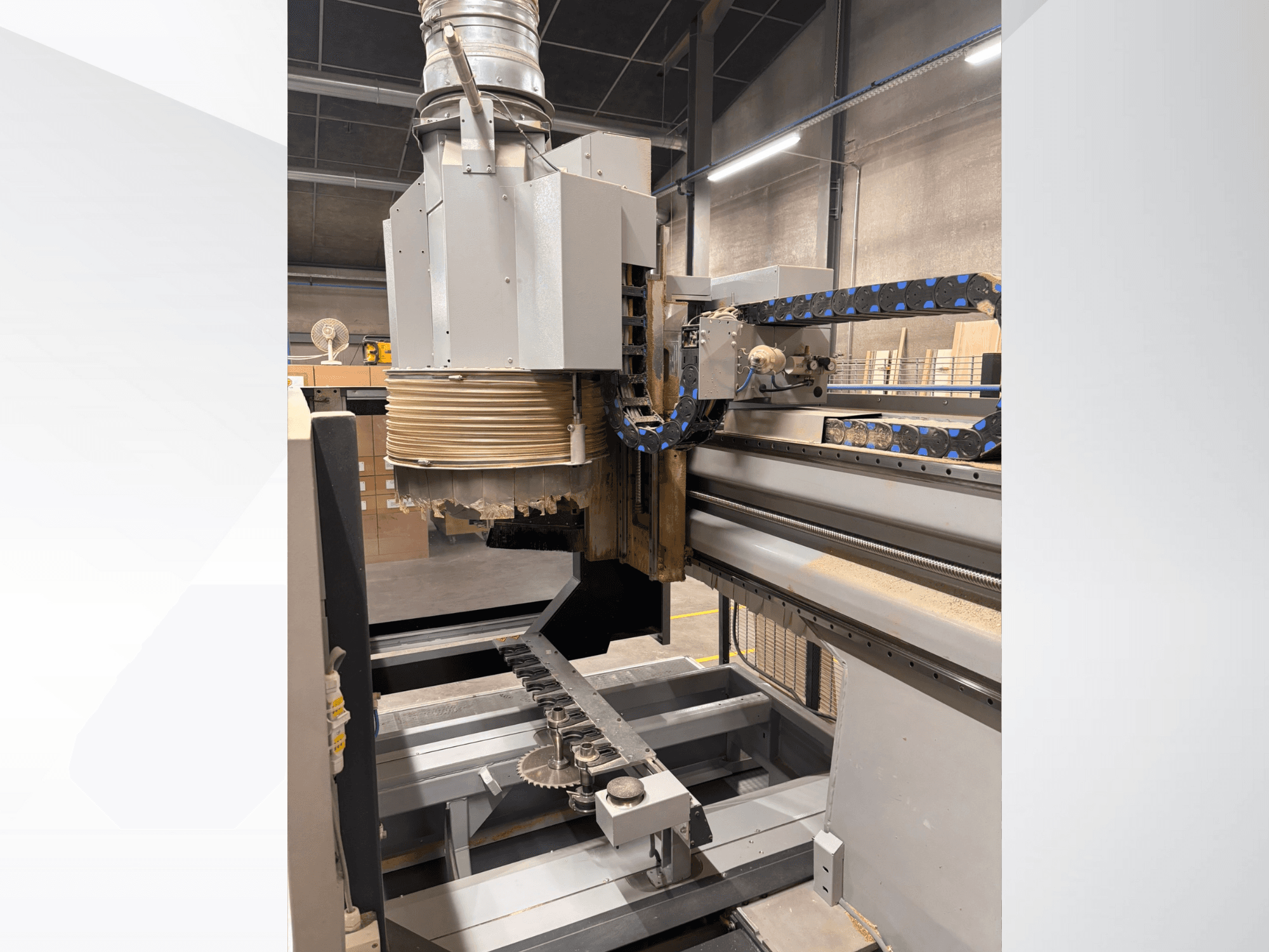 CNC-fúrógép nagy orsóval és szállítószalaggal, oldalnézetben, fafaragó szerszámok és gépalkatrészek bemutatásával.