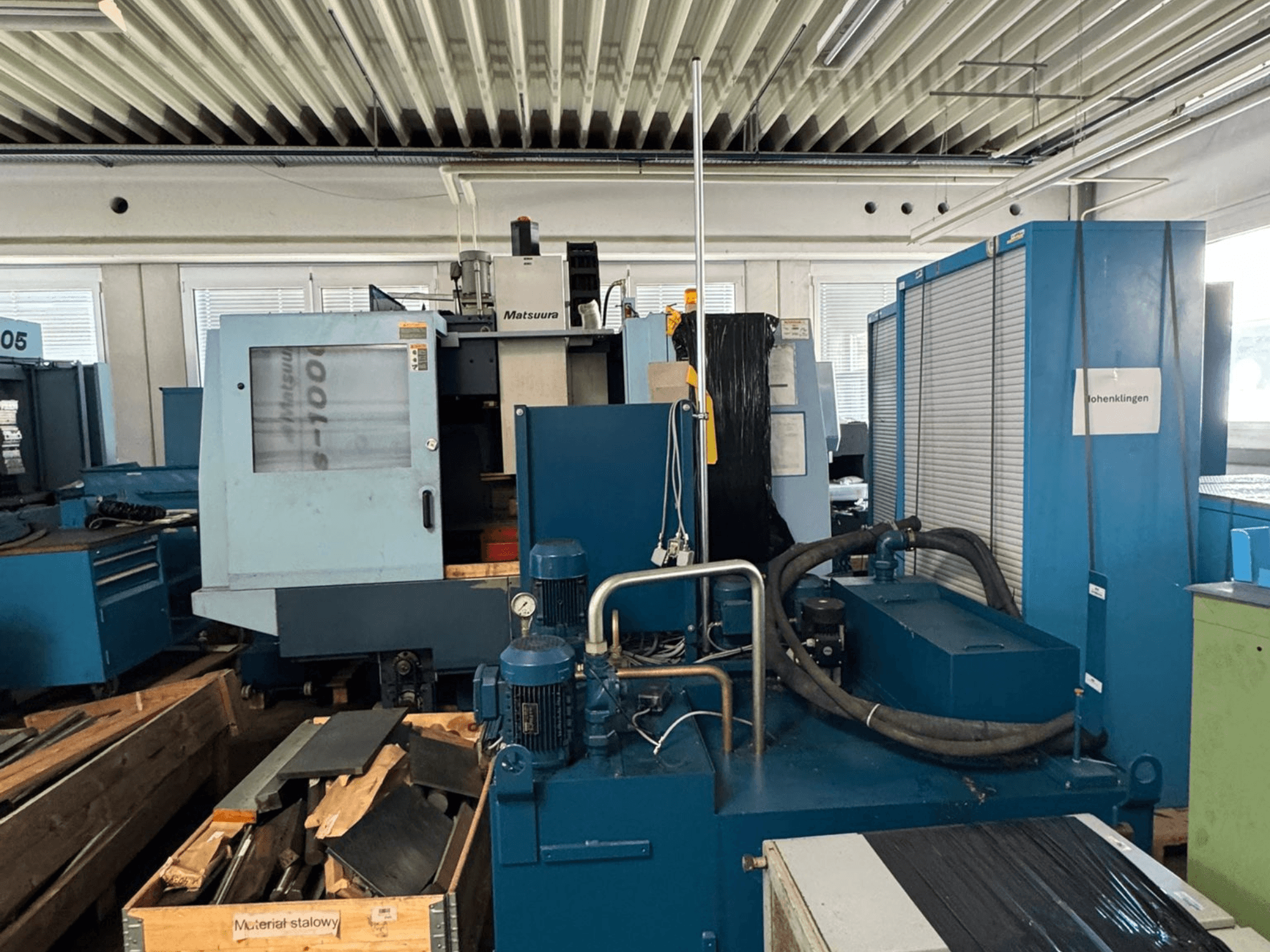 A Matsuura Vplus 1000/40 függőleges megmunkálóközpont elölnézete, amelyen láthatók a vezérlőelemek, a motorok és a környező műhely.