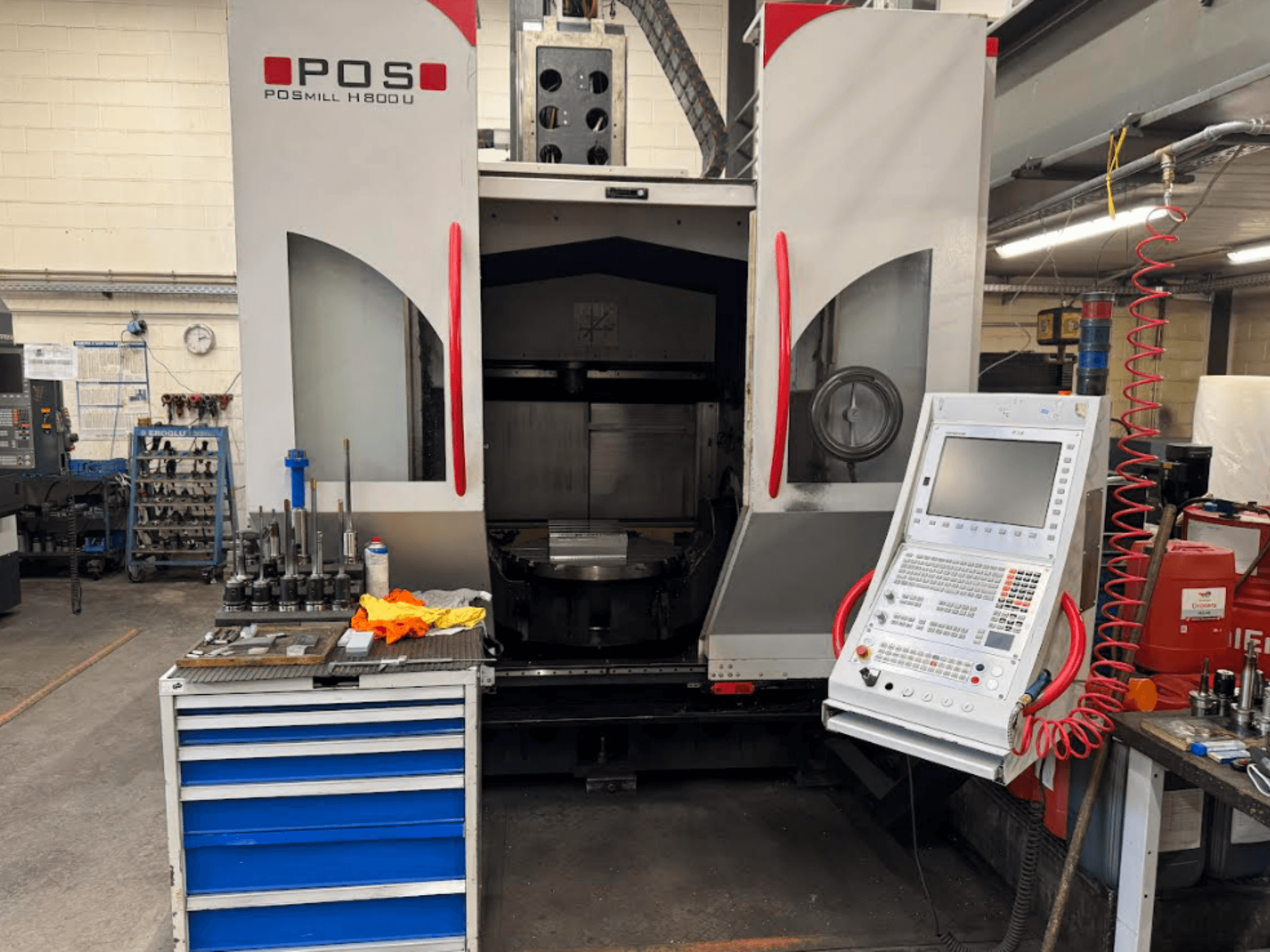 POSMILL H800 U CNC-gép szemből nézve, a vezérlőpanel és a munkaterület a közelben lévő szerszámokkal és berendezésekkel.