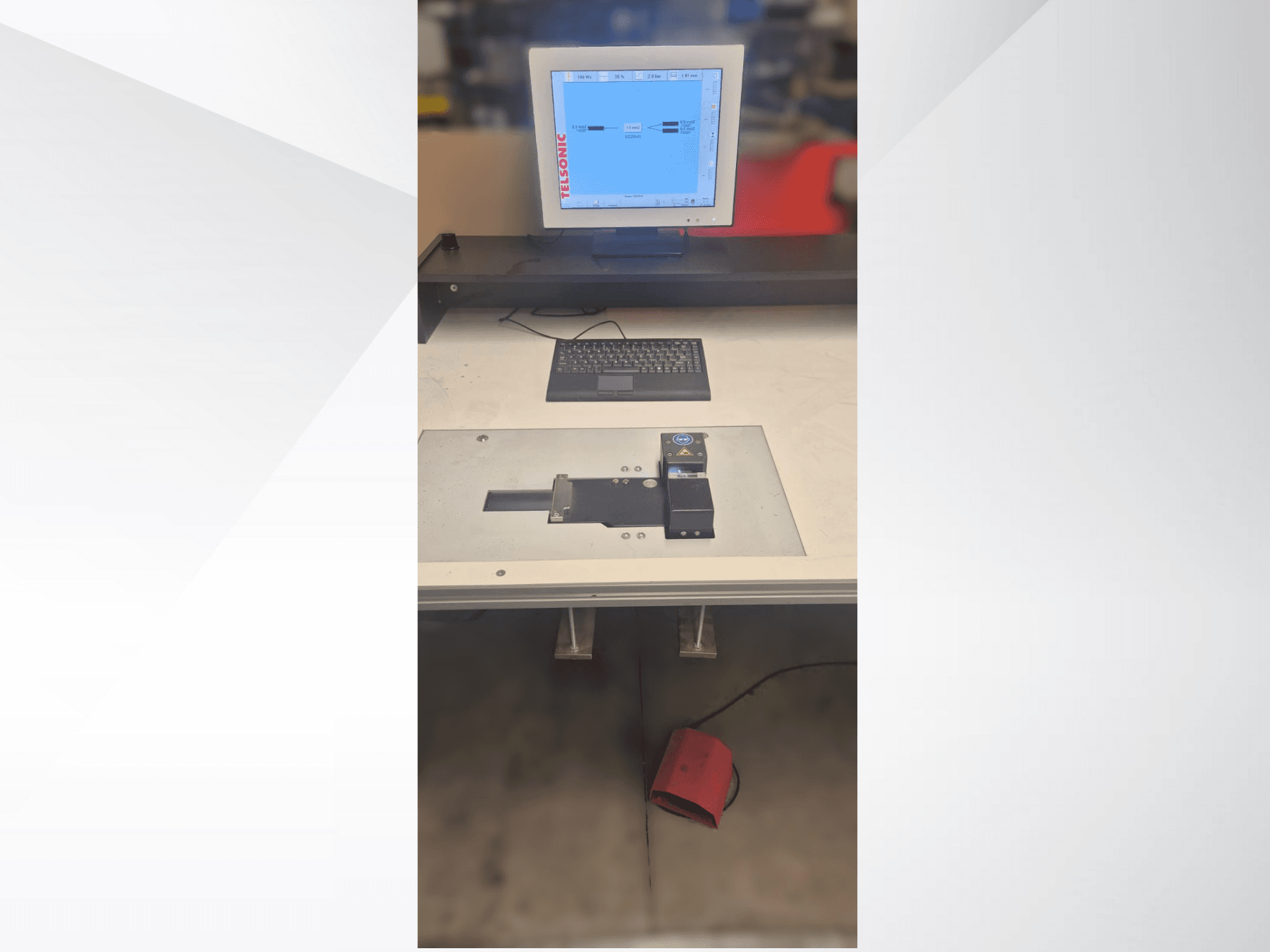 Egy tesztállomás felülről lefelé néző nézete számítógépes monitorral, billentyűzettel és egy gombot és egy zöld fényt tartalmazó vezérlőpanellel.