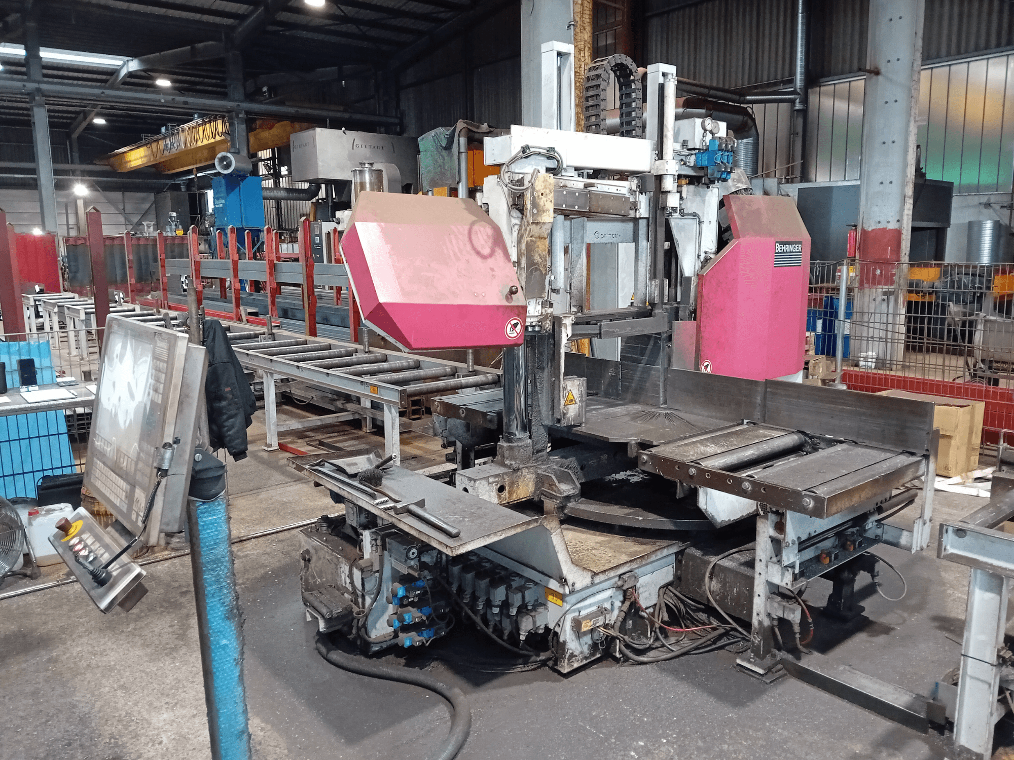 Behringer szalagfűrészgép egy gyárban, elölnézetben, nagyméretű vágólap és gombokkal ellátott kezelőpanel.