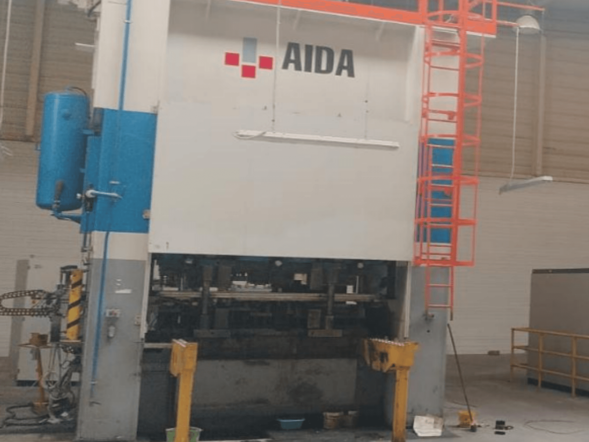 AIDA mechanikus bélyegzőprés 315/2MR/LD/TE3, elölnézet, a hidraulikus alkatrészek és a biztonsági létra bemutatása.