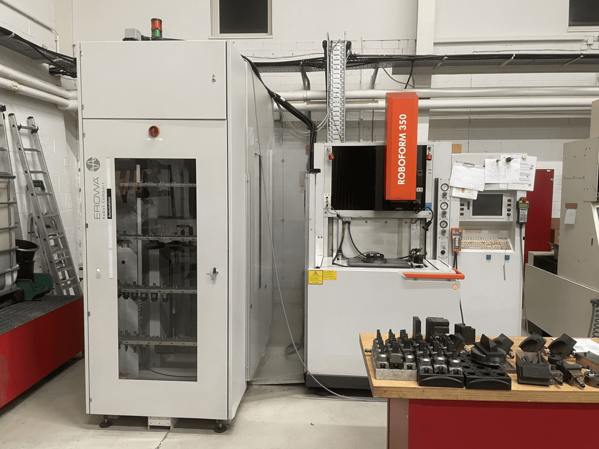 CHARMILLES Roboform 350 süllyesztéses szerszámsüllyesztő gép, elölnézetben, az asztalon elhelyezett szerszámokkal és a szomszédos berendezésekkel.