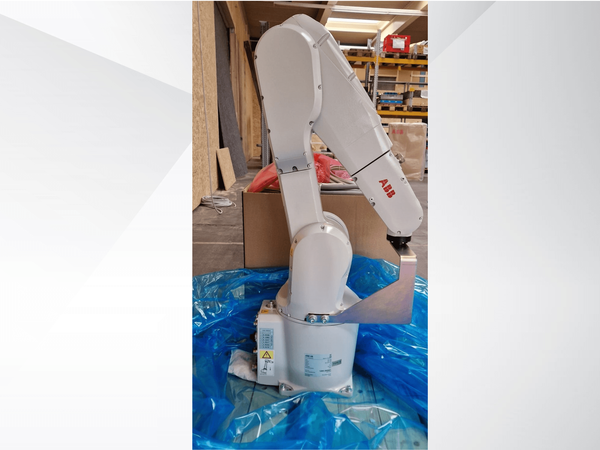 ABB robotkar modell, oldalnézetben kék ponyván, a csuklós ízületeket és a fém végberendezést mutatja, látható műszaki címkékkel.