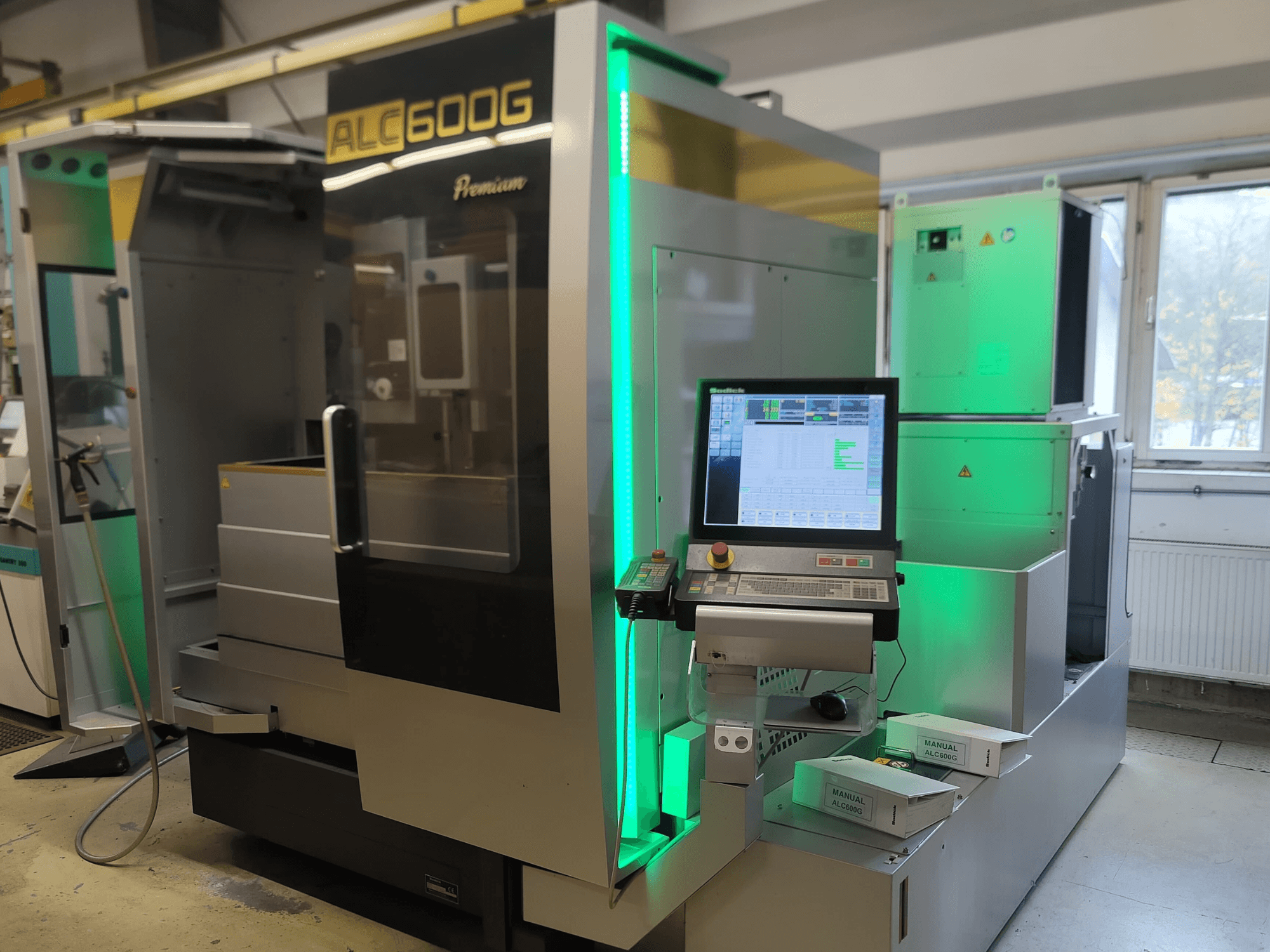 Sodick ALC600G Premium Wire EDM gép, előlnézet, a vezérlőpanel és a megvilágított külső részletek bemutatása.