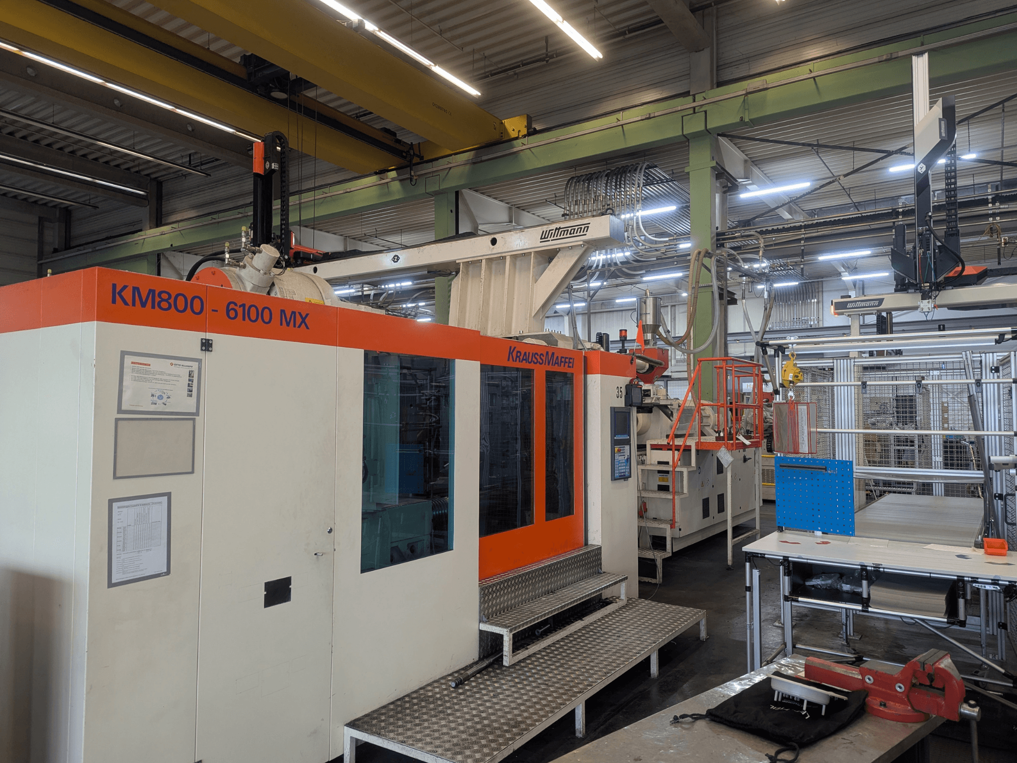 Krauss Maffei KM 800-6100MX hidraulikus fröccsöntőgép, előlnézet, a vezérlőpanel és az ipari beállítások bemutatása.