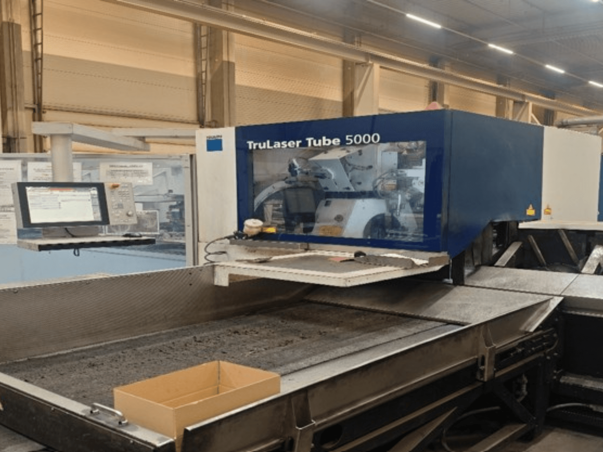 A TRUMPF TruLaser Tube 5000 elölnézete, amelyen látható a kezelőpanel és a vágási terület a precíz csővágási műveletekhez.