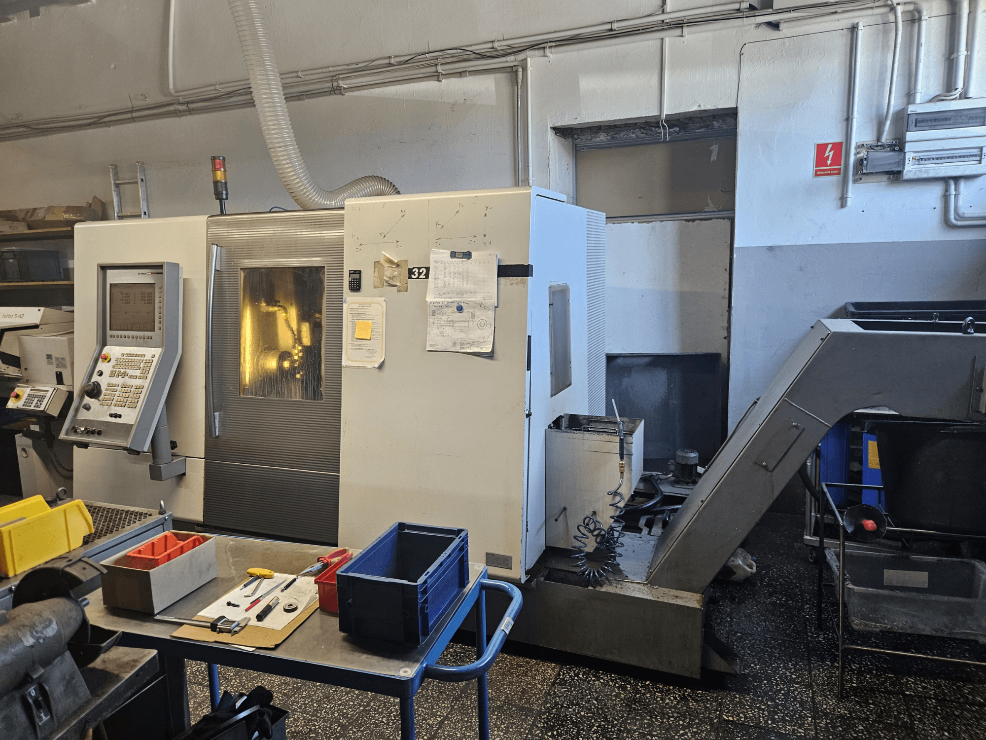 Többorsós esztergagép DMG GILDEMEISTER Sprint 32 lineáris, elölnézetben egy műhelyben, a kezelőpanel és a szerszámok láthatóak.