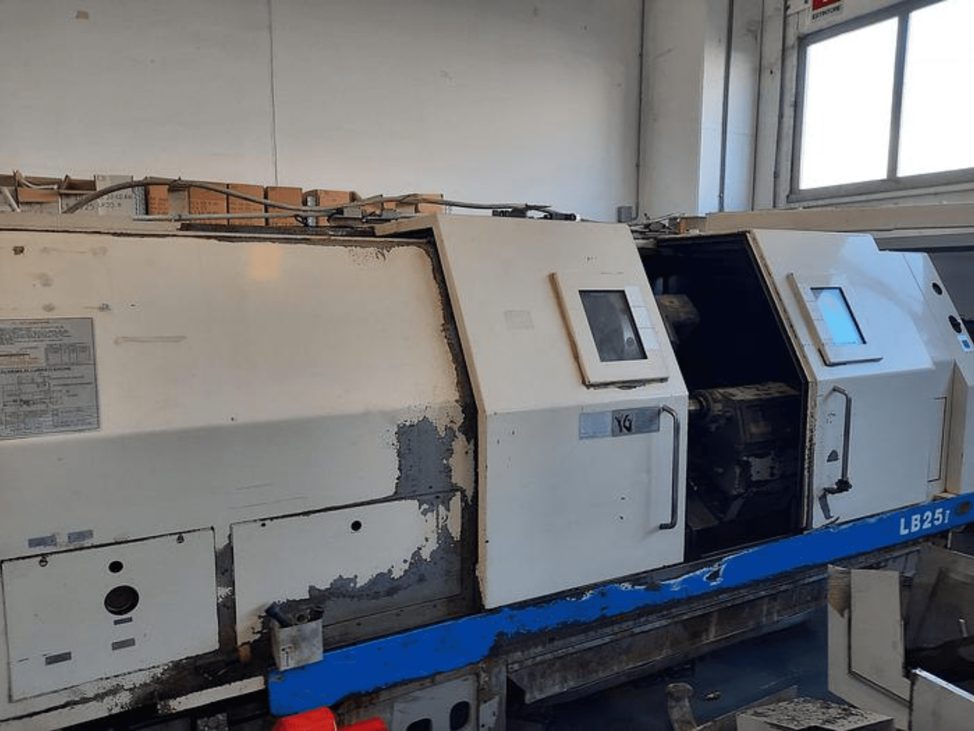 Használt LB251 esztergagép, oldalnézetben kopott külső, nyitott panel, amely feltárja a belső mechanizmust és a kezelőszerveket.