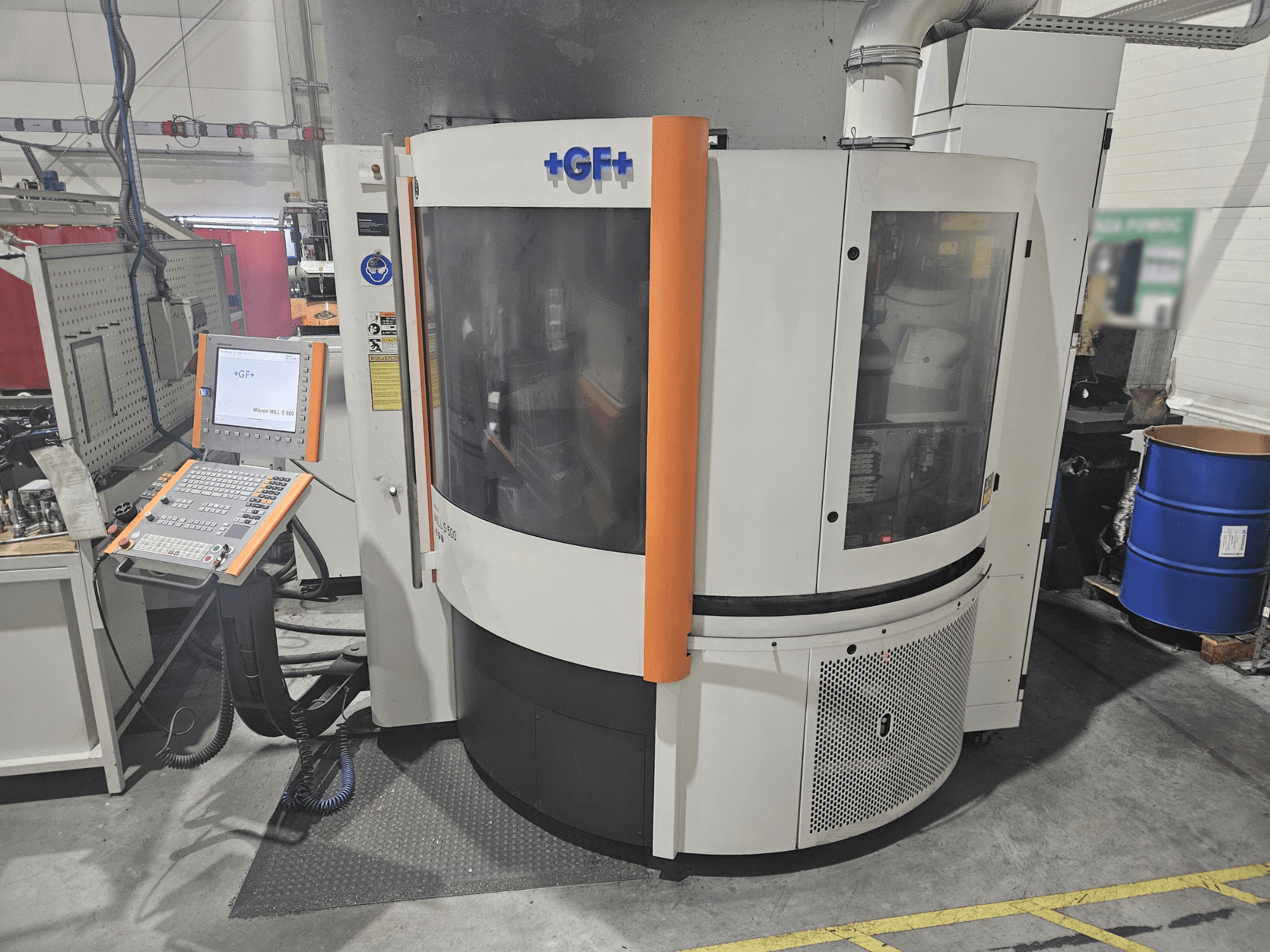 GF Machining Solutions szerszámgép vezérlőpanellel, előlnézet; átlátszó panel, narancssárga ékezetek és ipari beállítások.