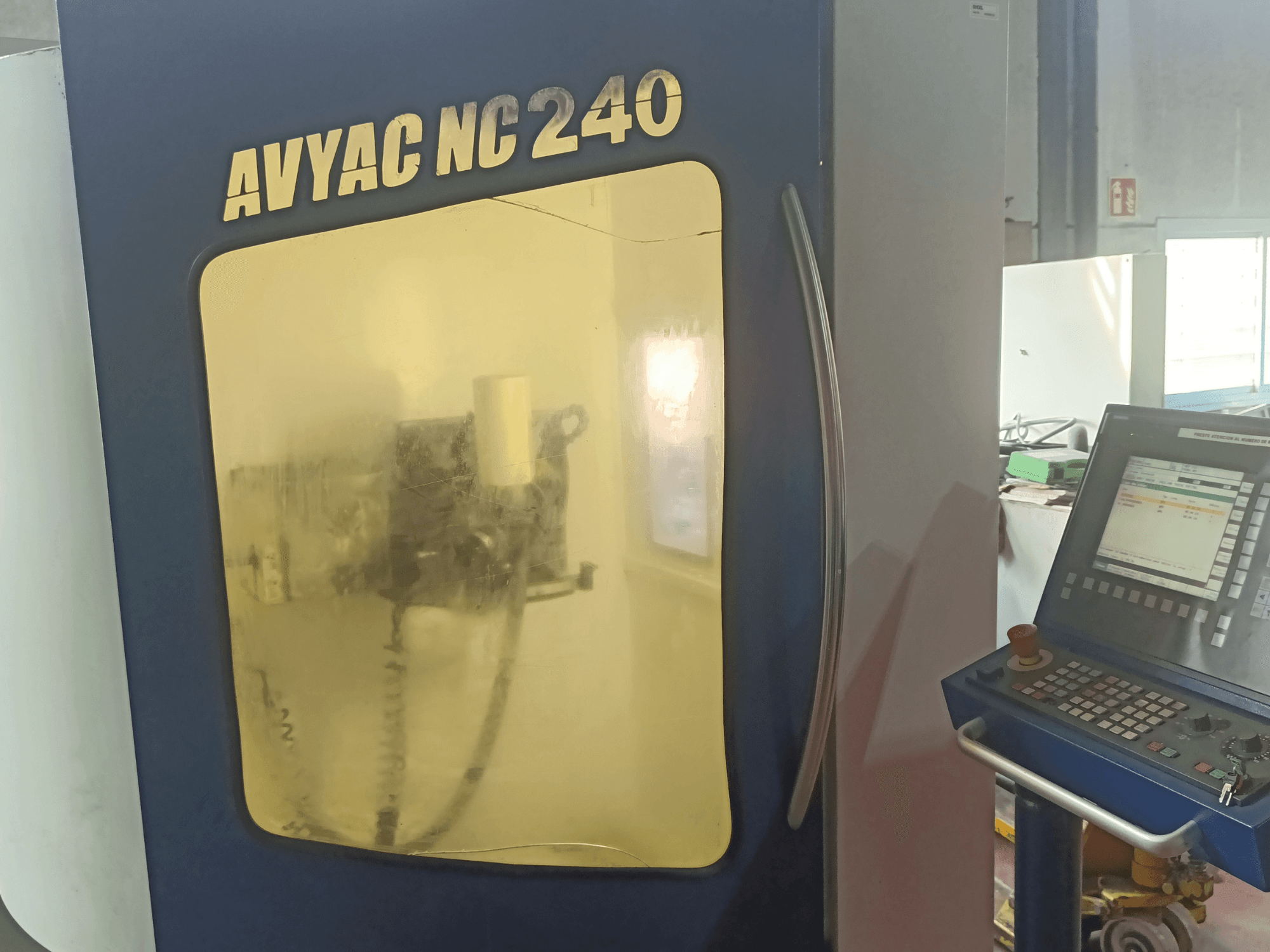 AVYAC NC240 hengeres köszörűgép, oldalnézetben a vezérlőpanel és az ablakon keresztül részben látható köszörűterület.