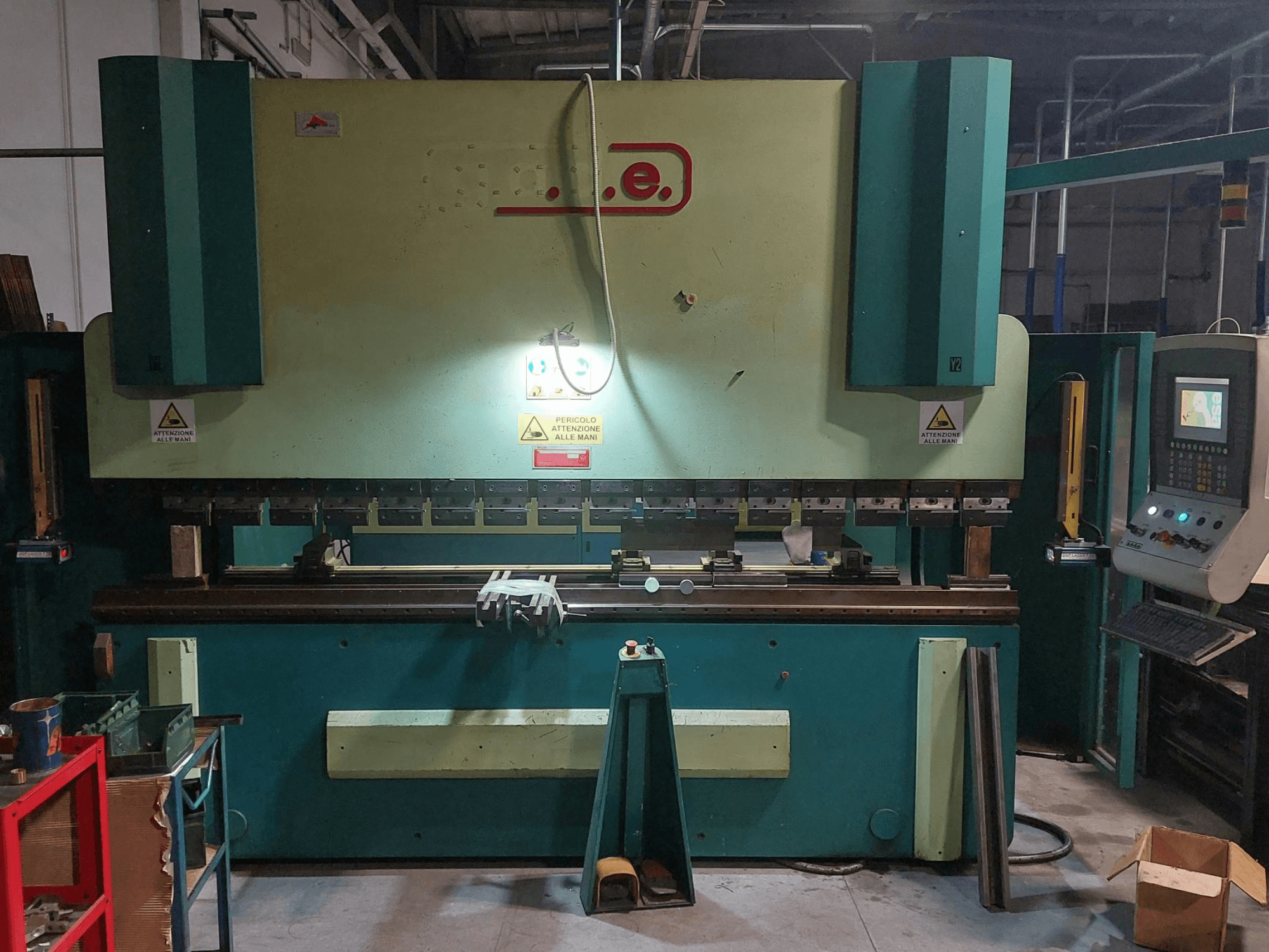 A Gade PS-C 3120 hajlítógép elölnézete, amelyen látható a vezérlőpanel, a biztonsági jelzések, valamint a szerszámokkal és anyagokkal ellátott munkaterület.